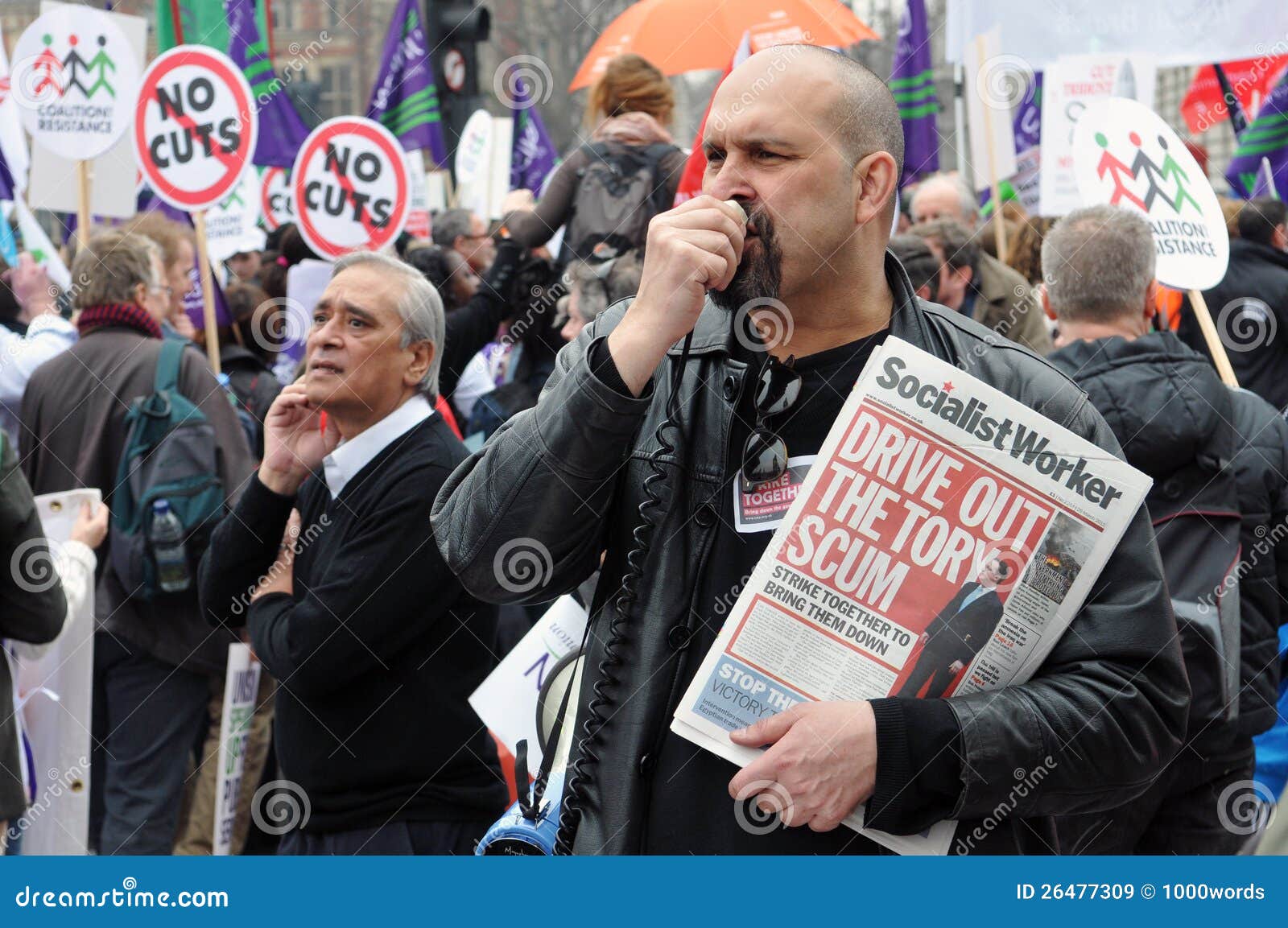 Het Protest van de Strengheid van Londen. Een mens verkoopt exemplaren van Socialistische Arbeider tijdens een grote strengheidsverzameling op 26 Maart, 2011 in Londen, het UK. Sloten aan de geschatte 250.000 mensen zich bij het TUC georganiseerde protest.