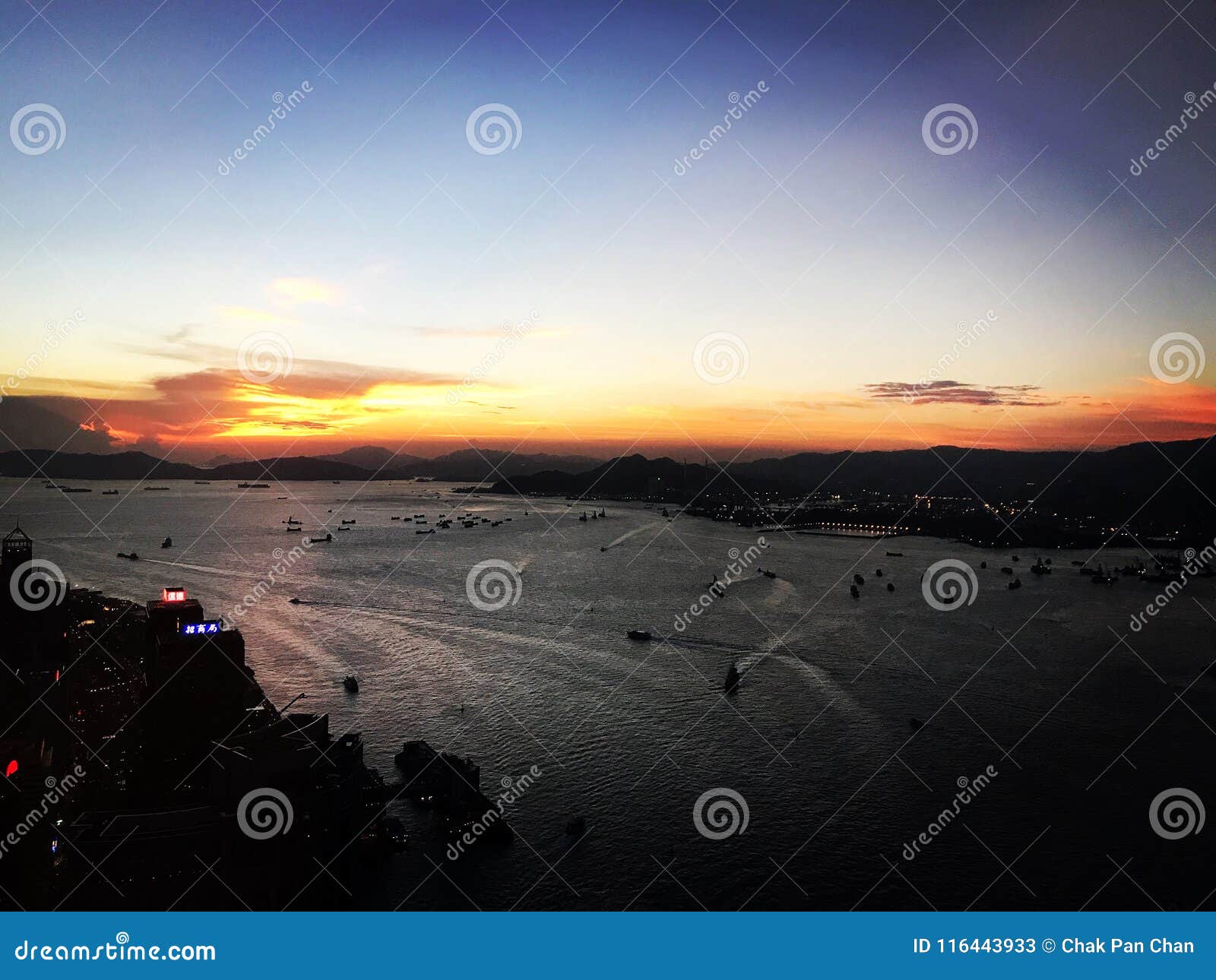Het verrukken van de Zonsondergang van HK over Victoria Harbor. Betoverende die zonsondergangfoto uit het langste gebouw in Hong Kong Island wordt genomen, die op Victoria Harbor toezicht houden De gouden horizon over het overzees rekt zich over de overkant van de haven uit
