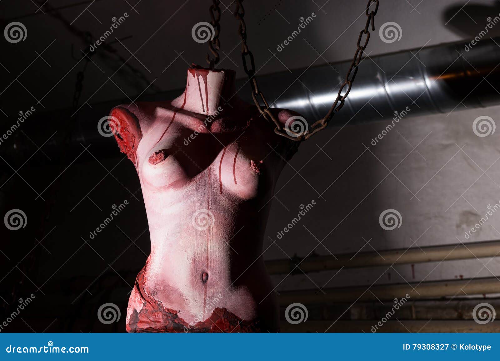 Het verscheurde vrouwelijke torso hangen van kettingen in kelderverdieping 