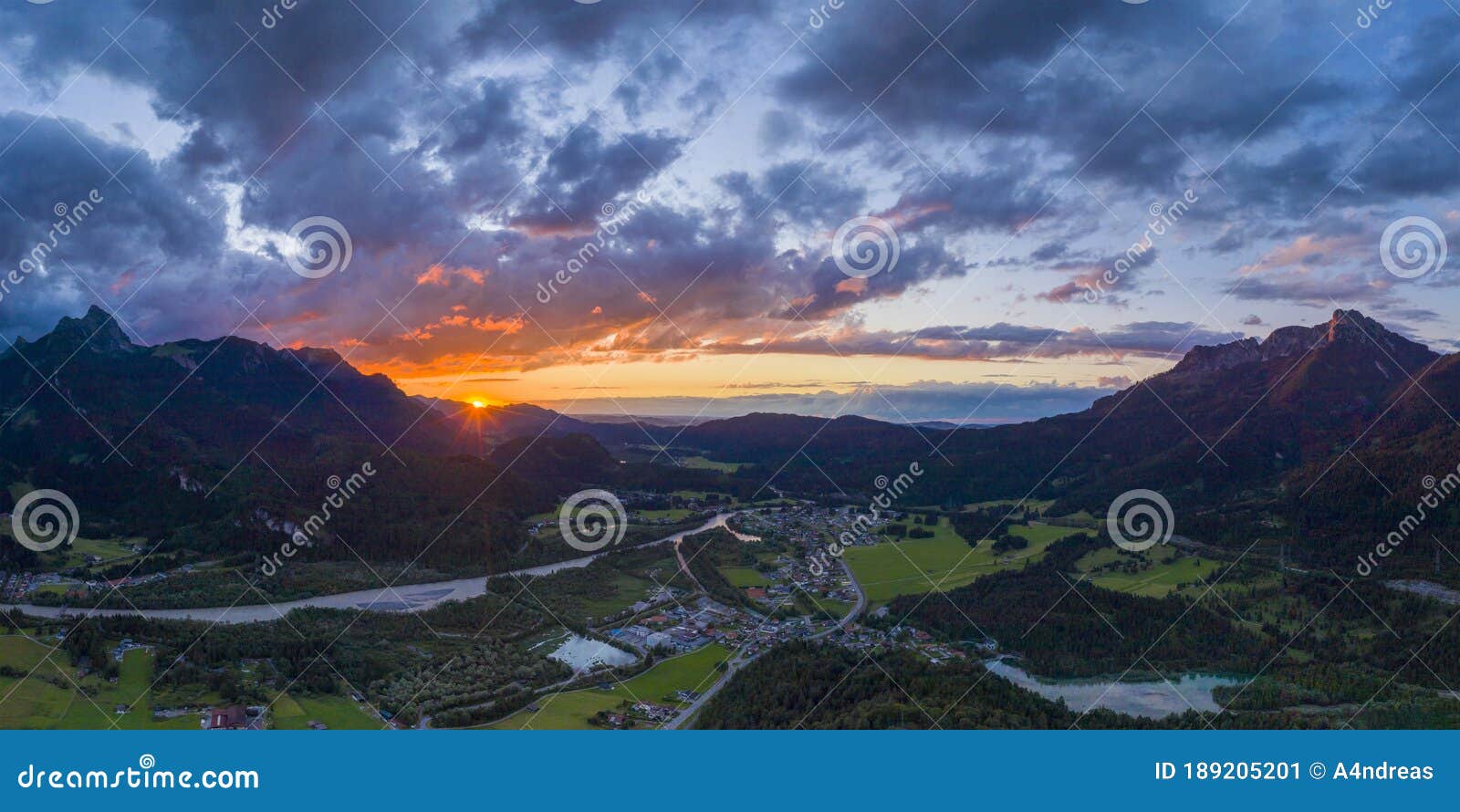 hiding sun behind mountain chain hahnenkamm with view to village pflach