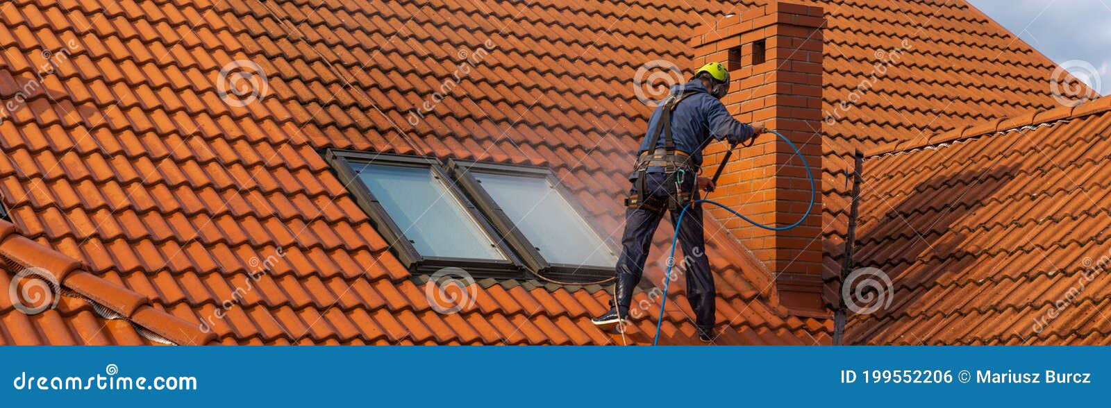 high-altitude worker washing the roof with pressurized water