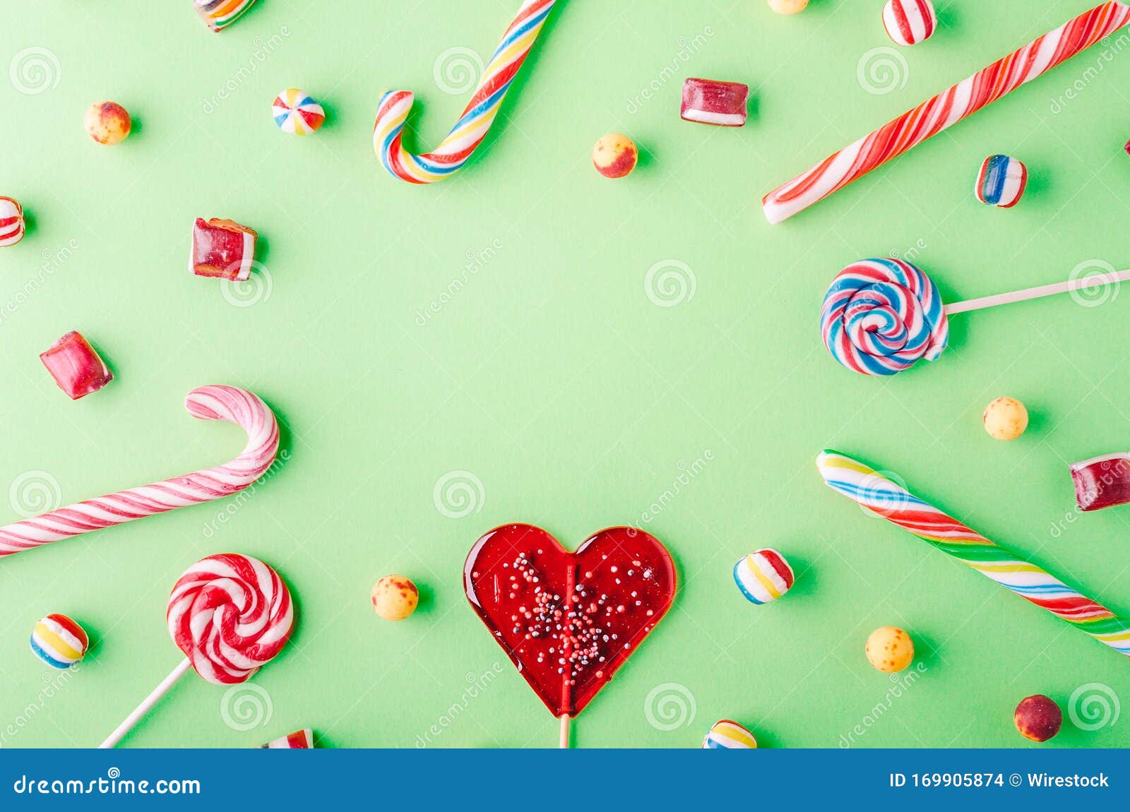 High Angle Shot of Candy Canes and Lollipops on a Green Background ...