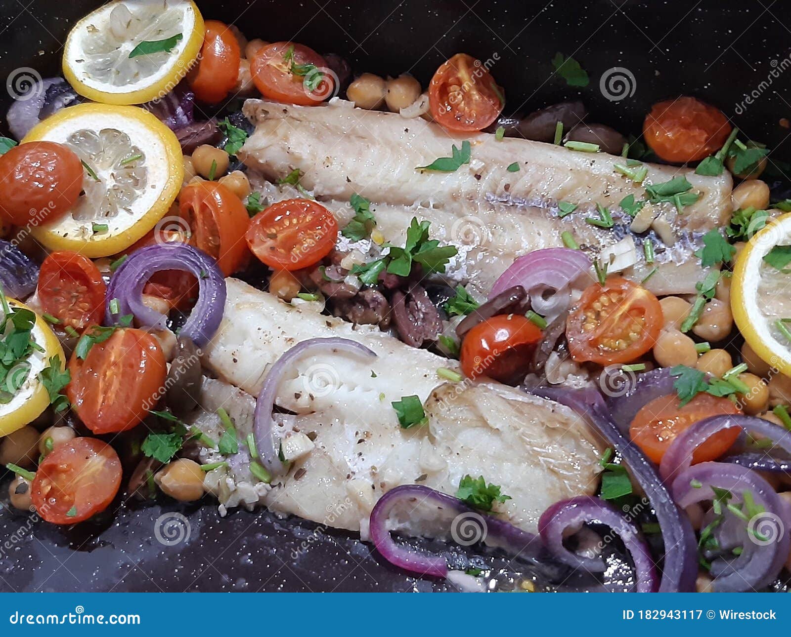 High Angle Shot Of Cooked Fish With Lemons Tomatoes And Onions Stock