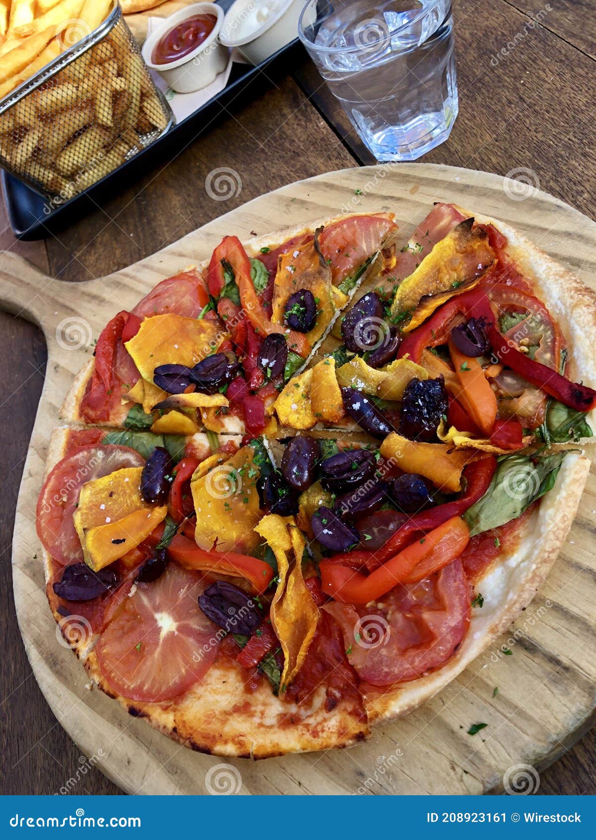 high angle shot of a large pizza on a wooden foote with vegetables