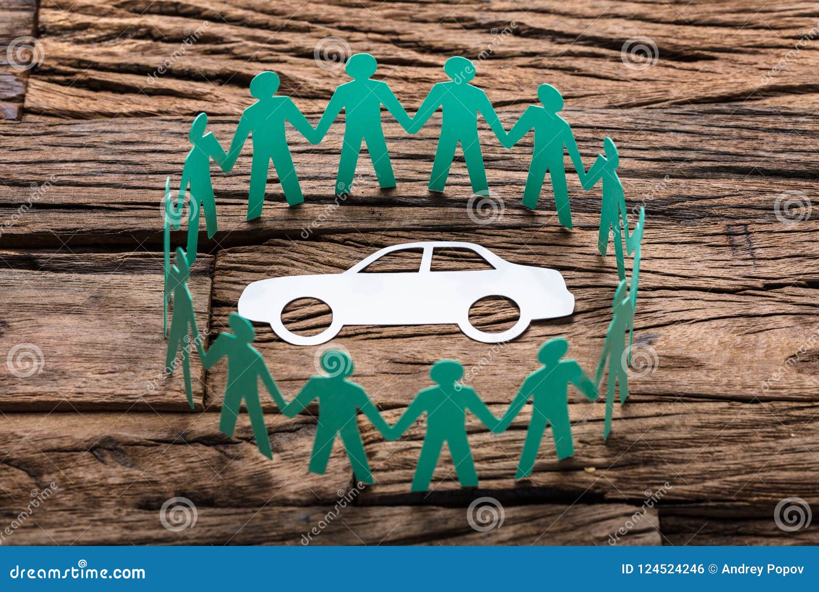 green paper team surrounding car on wooden table
