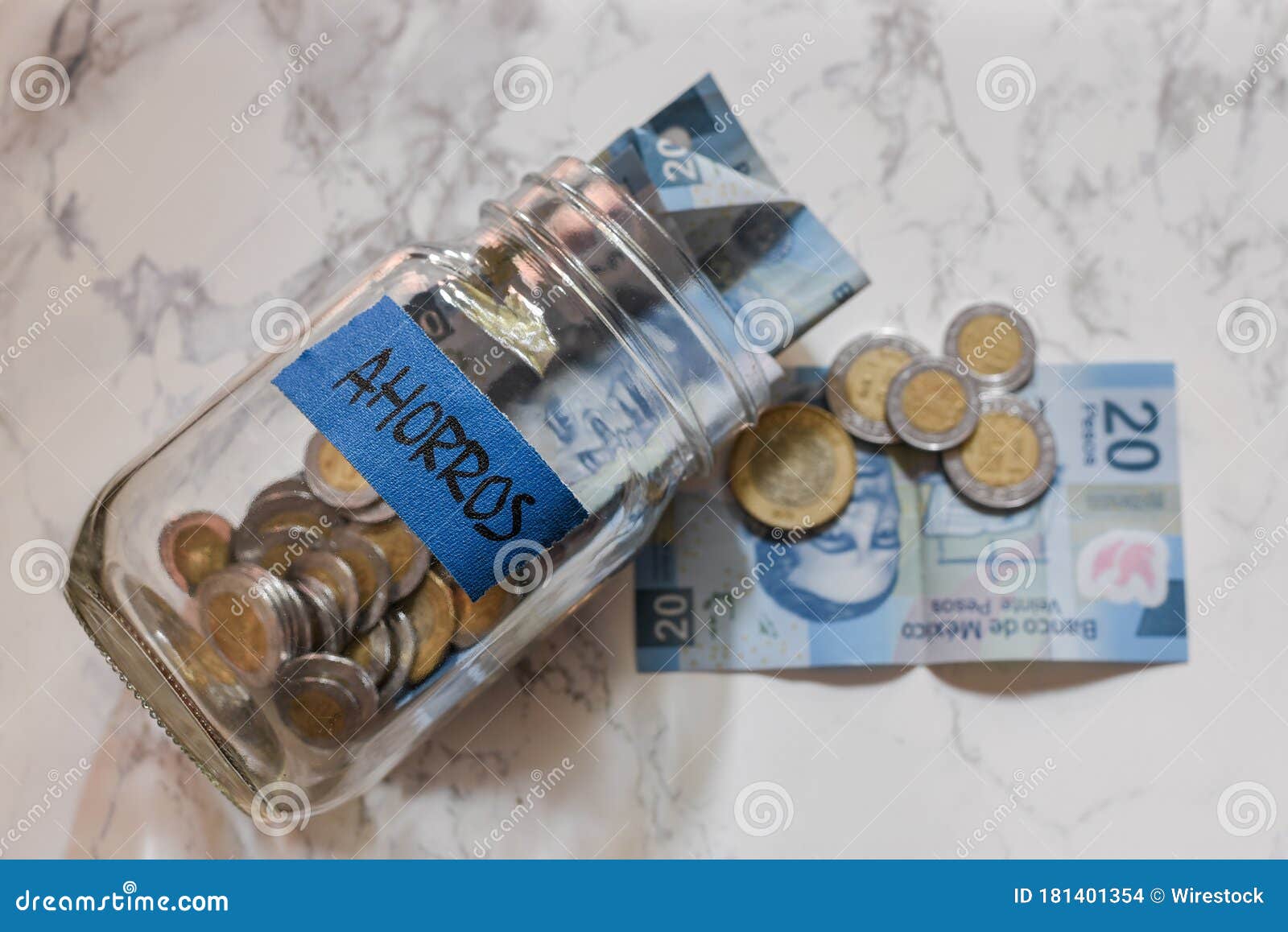 high angle view of pesos and coins in a jar with a [ahorros - savings] sticker on it on the table