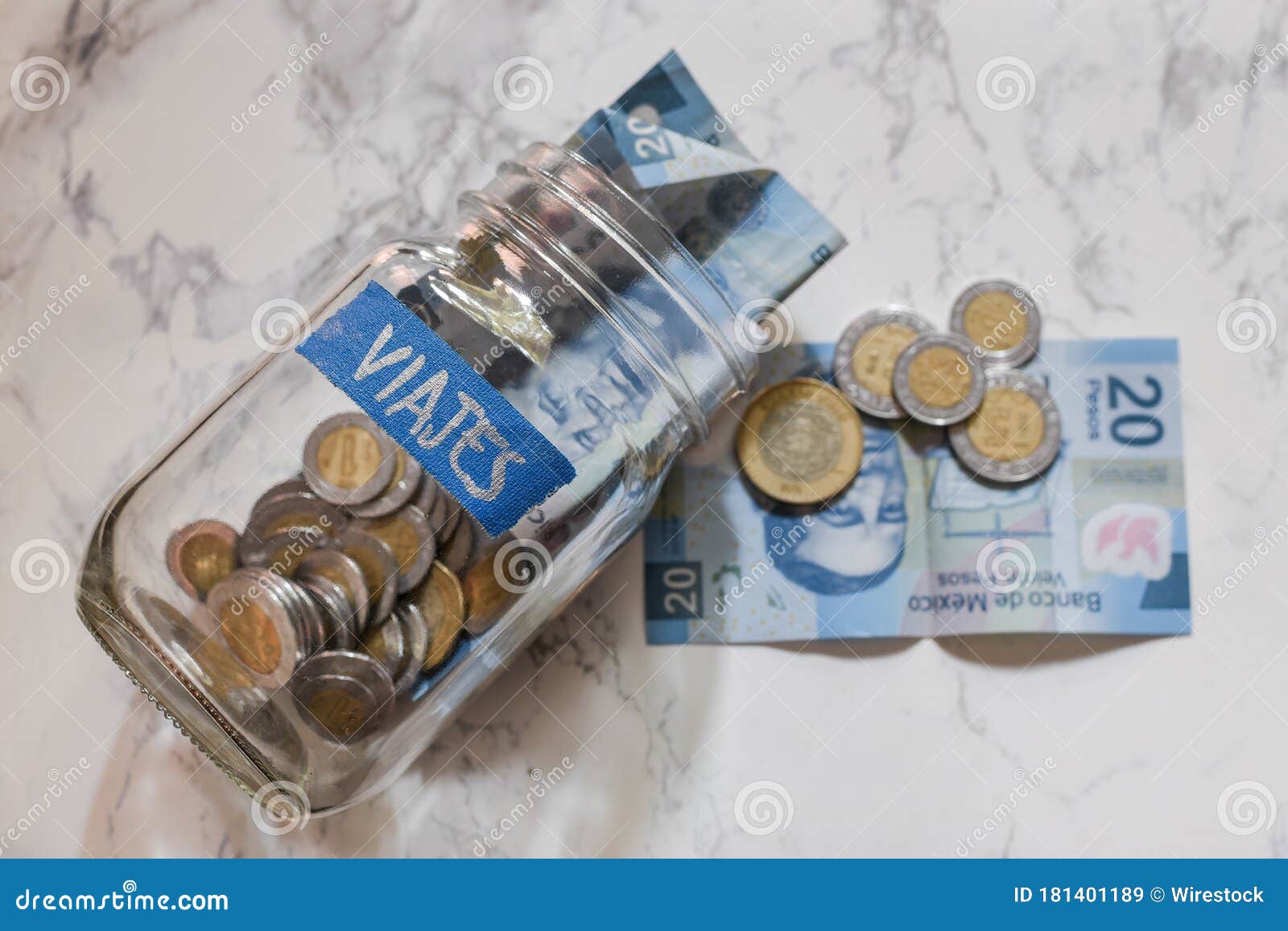 high angle view of pesos and coins in a jar with a [viajes - travels] sticker on it on the table