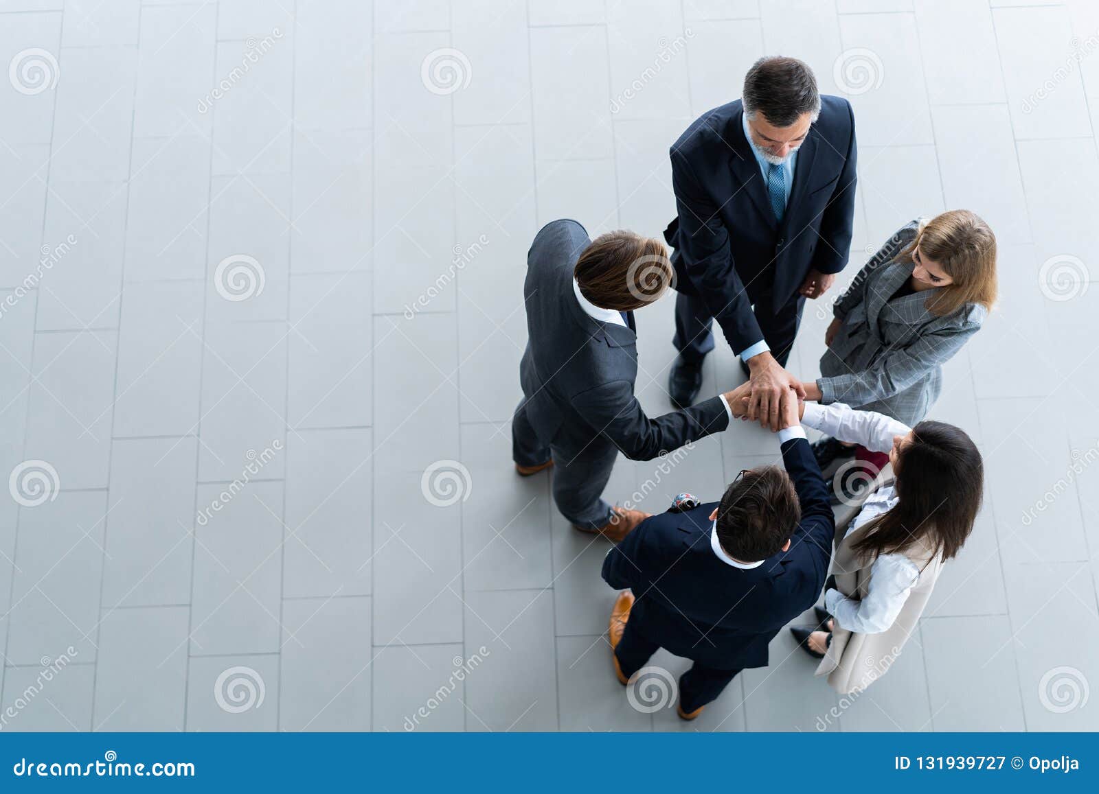 high angle view of a team of united coworkers standing with their hands together in a huddle in the modern office