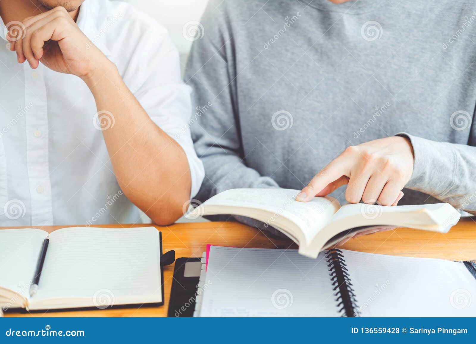 high school or college students studying and reading together in library