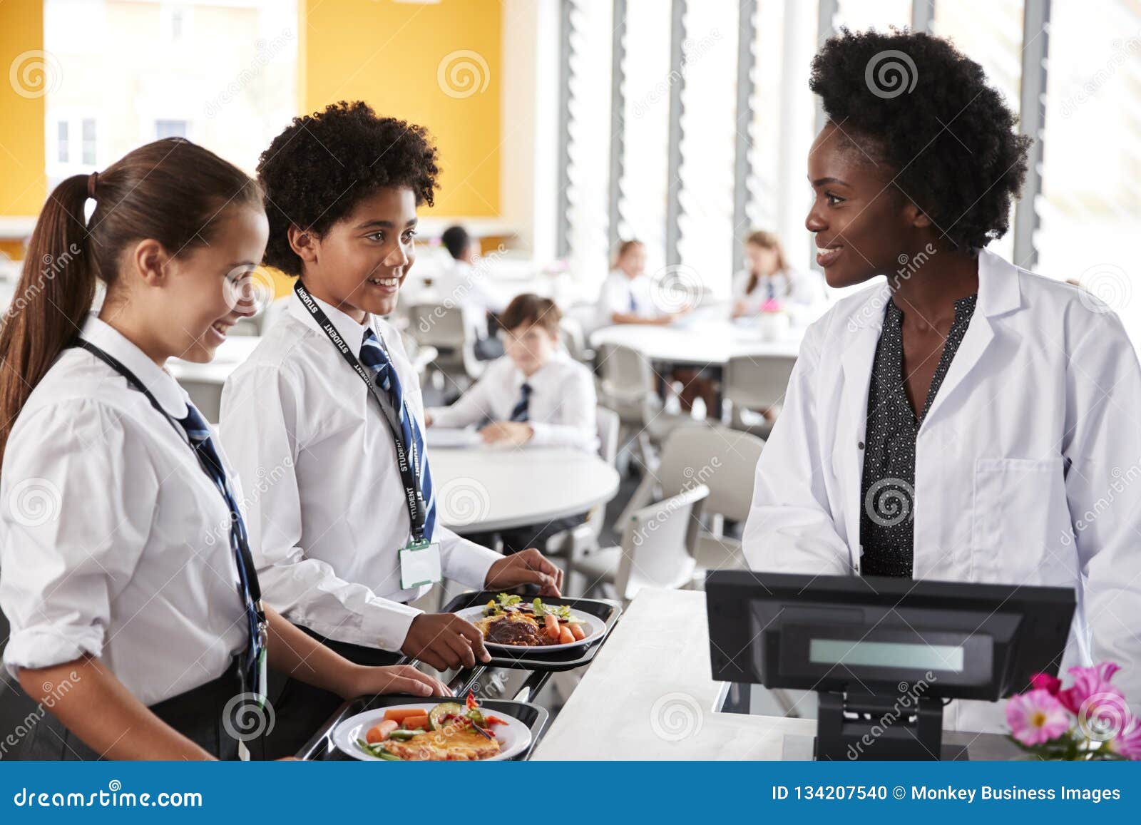 high school students wearing uniform paying for meal in cafeteria