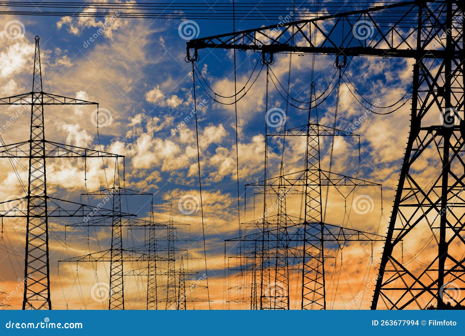 high voltage pylons for electricity and power against sky with dramatic clouds
