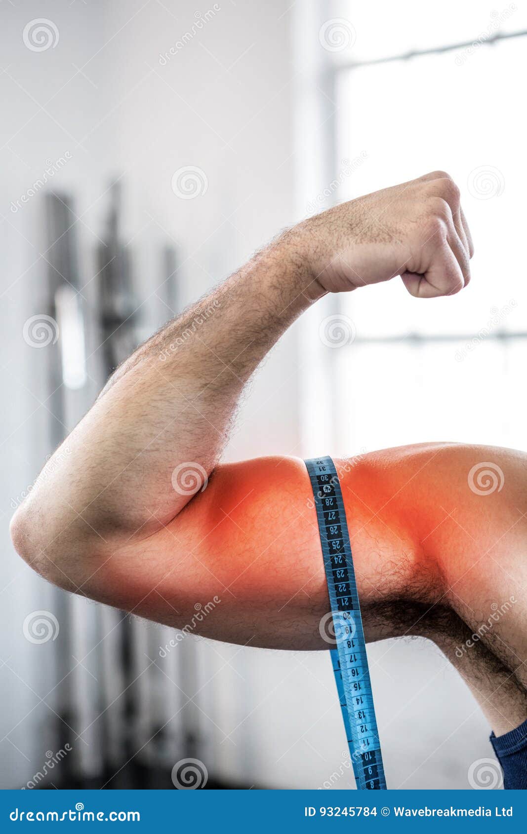 Highlighted Arm of Man Measuring Biceps with Measuring Tape Stock Photo