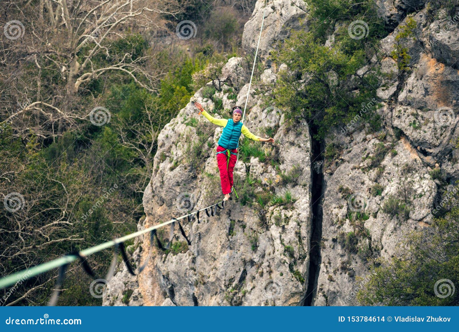 Eine Frau geht entlang einen ausgedehnten Riemen Highline in den Bergen Frau f?ngt Balance Leistung eines Drahtseilwanderers in der Natur