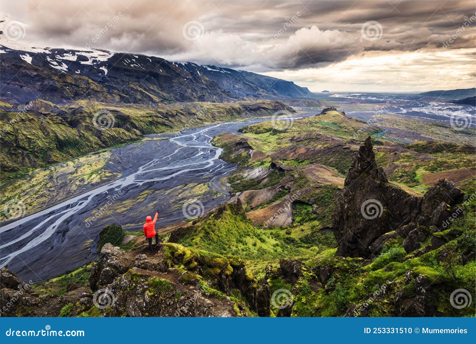 hiker man in red jacket standing on peak of valahnukur viewpoint with mountain valley and krossa river in icelandic highlands at