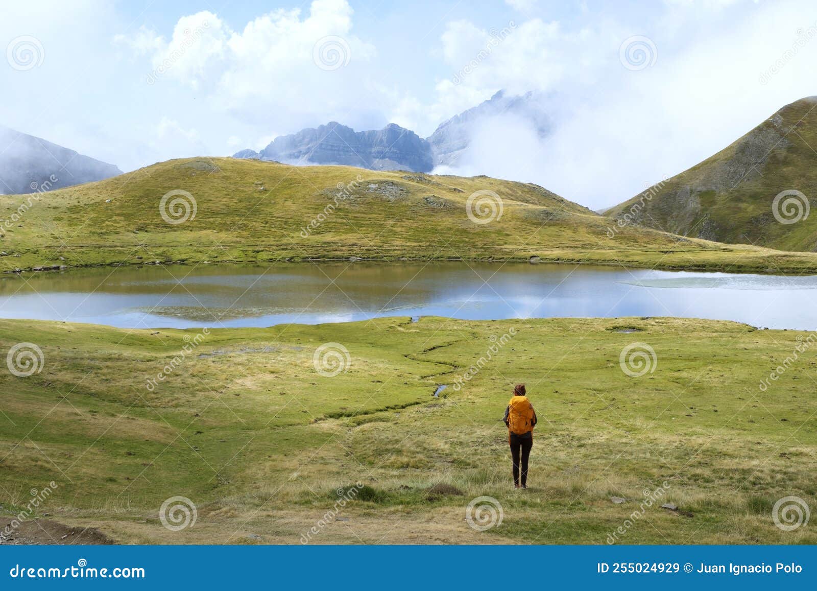 hiker with yellow backpack in the ibon de escalar, western valleys natural park, huesca pyrenees