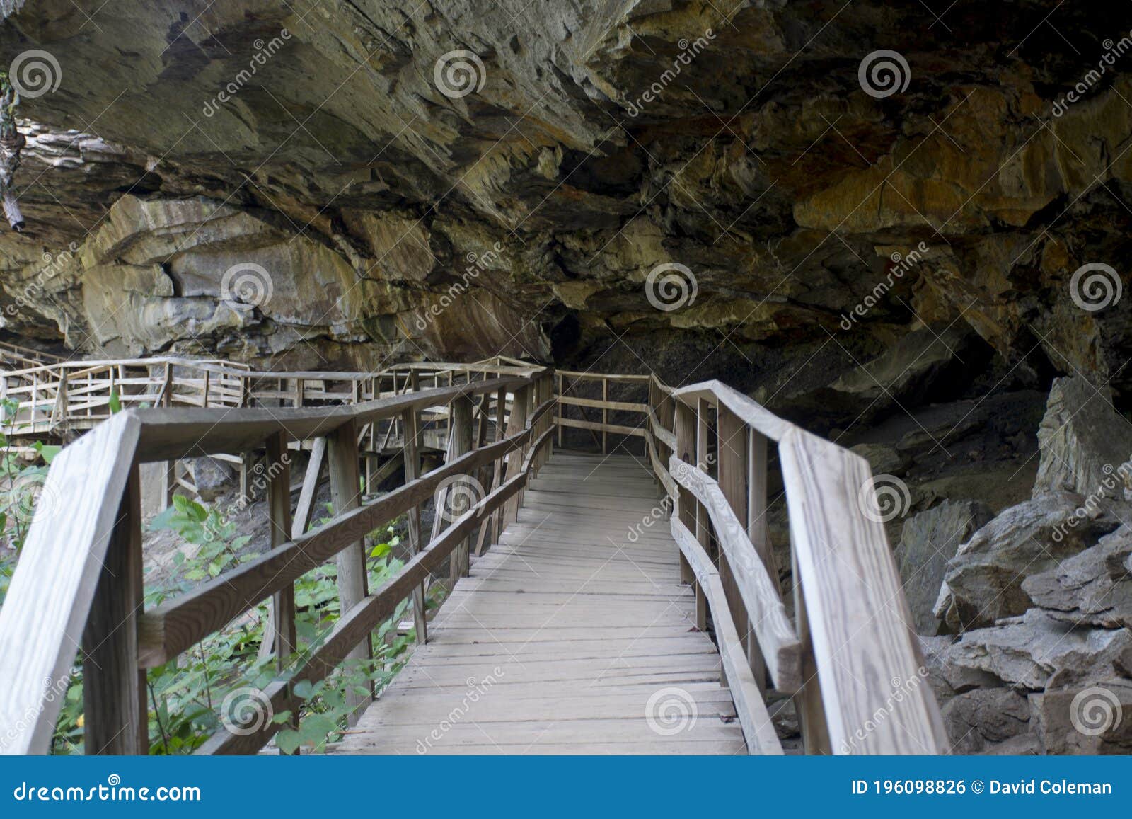 hiking trail boardwalk under rocky overhang
