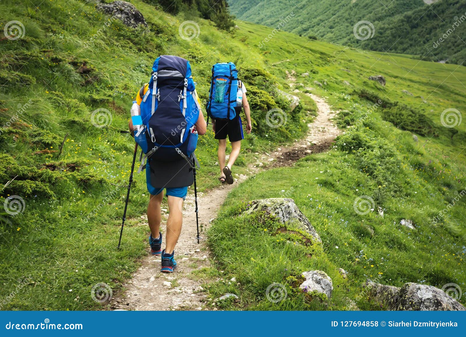 hiking trail in svaneti region, georgia. two hikers men walk on trek in mountain. tourists with backpacks hike in highlands