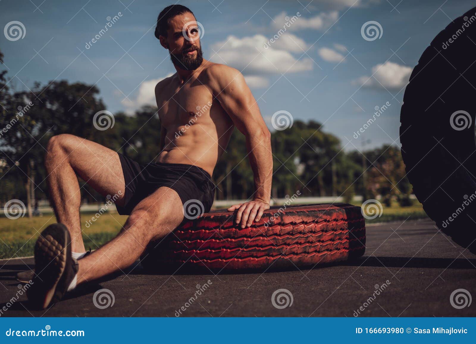 hipster athlete resting on the tire afte workout