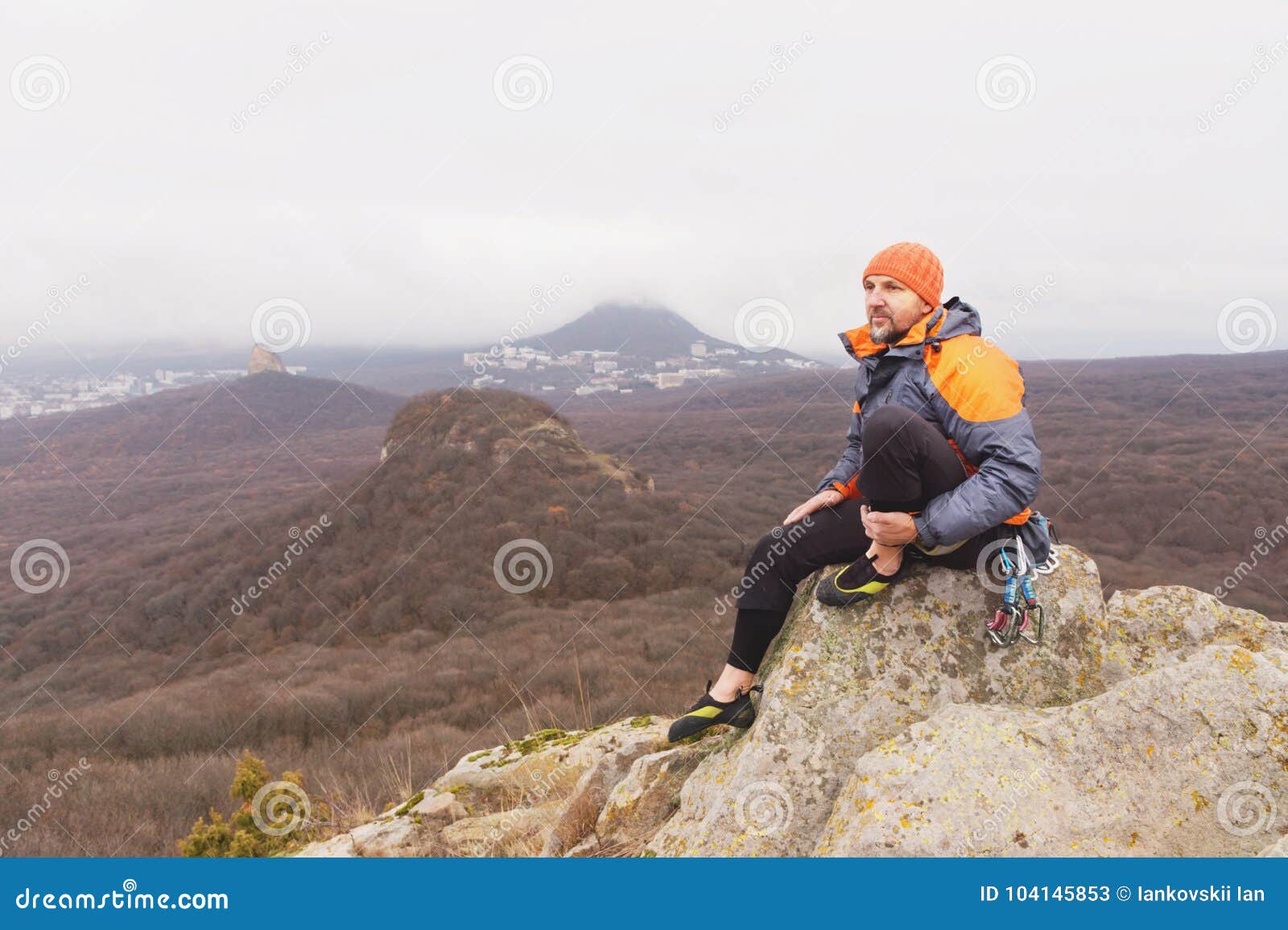 Hipster a Climber in a Down Jacket and a Knitted Cap Sits and Rests