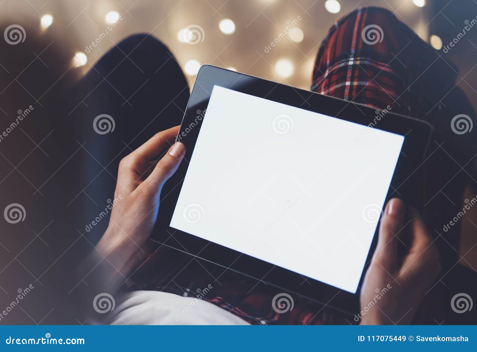 hipster girl using tablet technology in home atmosphere, person holding computer on background glow bokeh christmas illimination,