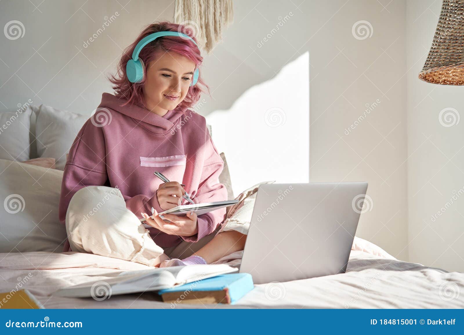 hipster teen girl student with pink hair watch online webinar learning in bed.