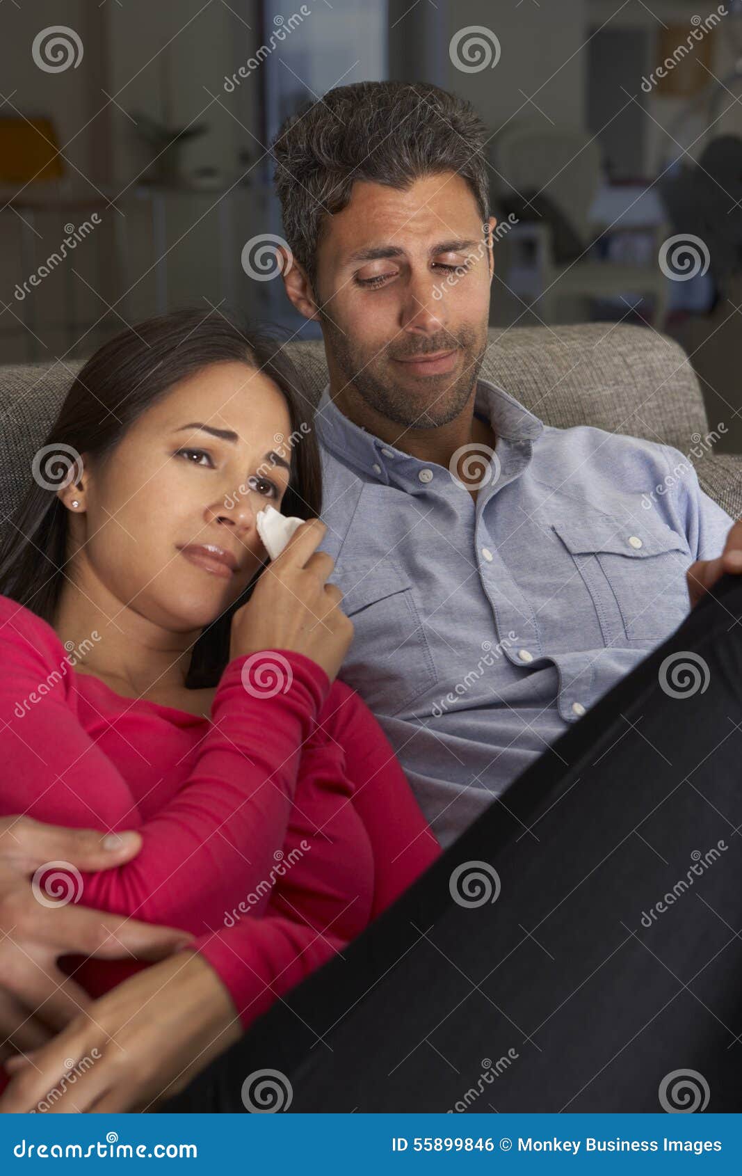 Hispanic Couple On Sofa Watching Sad Movie On TV