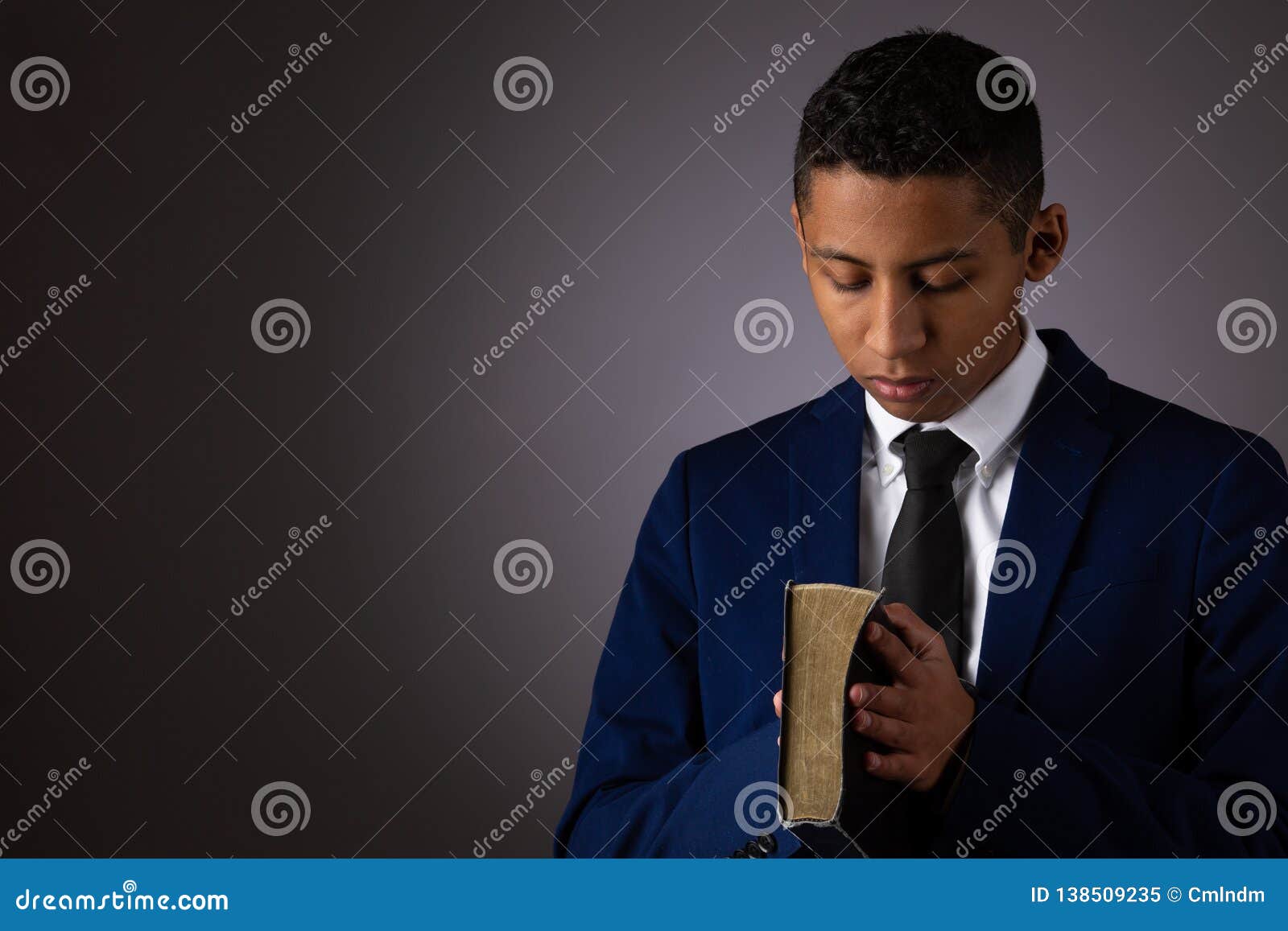 hispanic teenager boy seeking to commune with god via prayer and holding the holy bible
