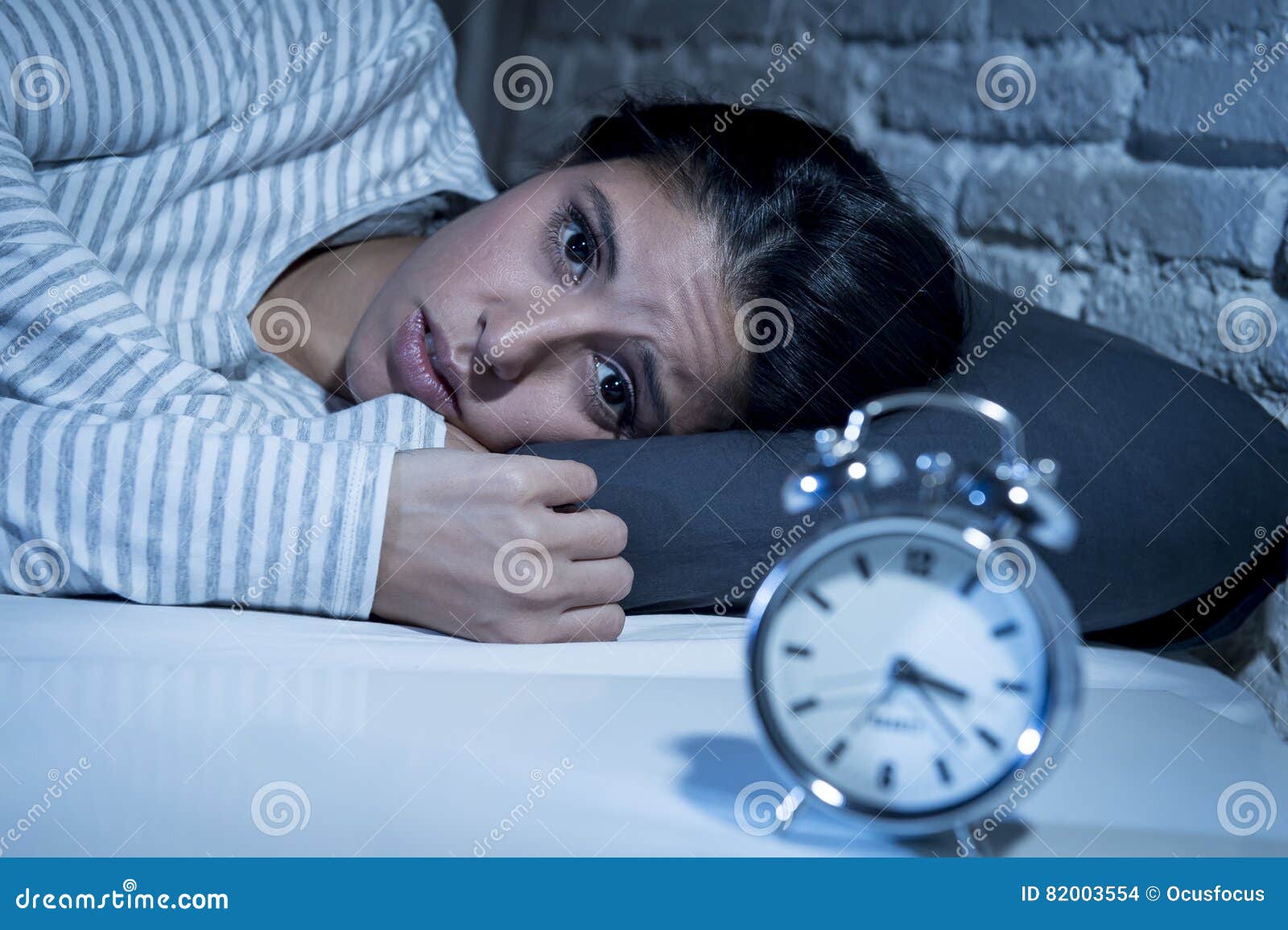 hispanic woman at home bedroom lying in bed late at night trying to sleep suffering insomnia