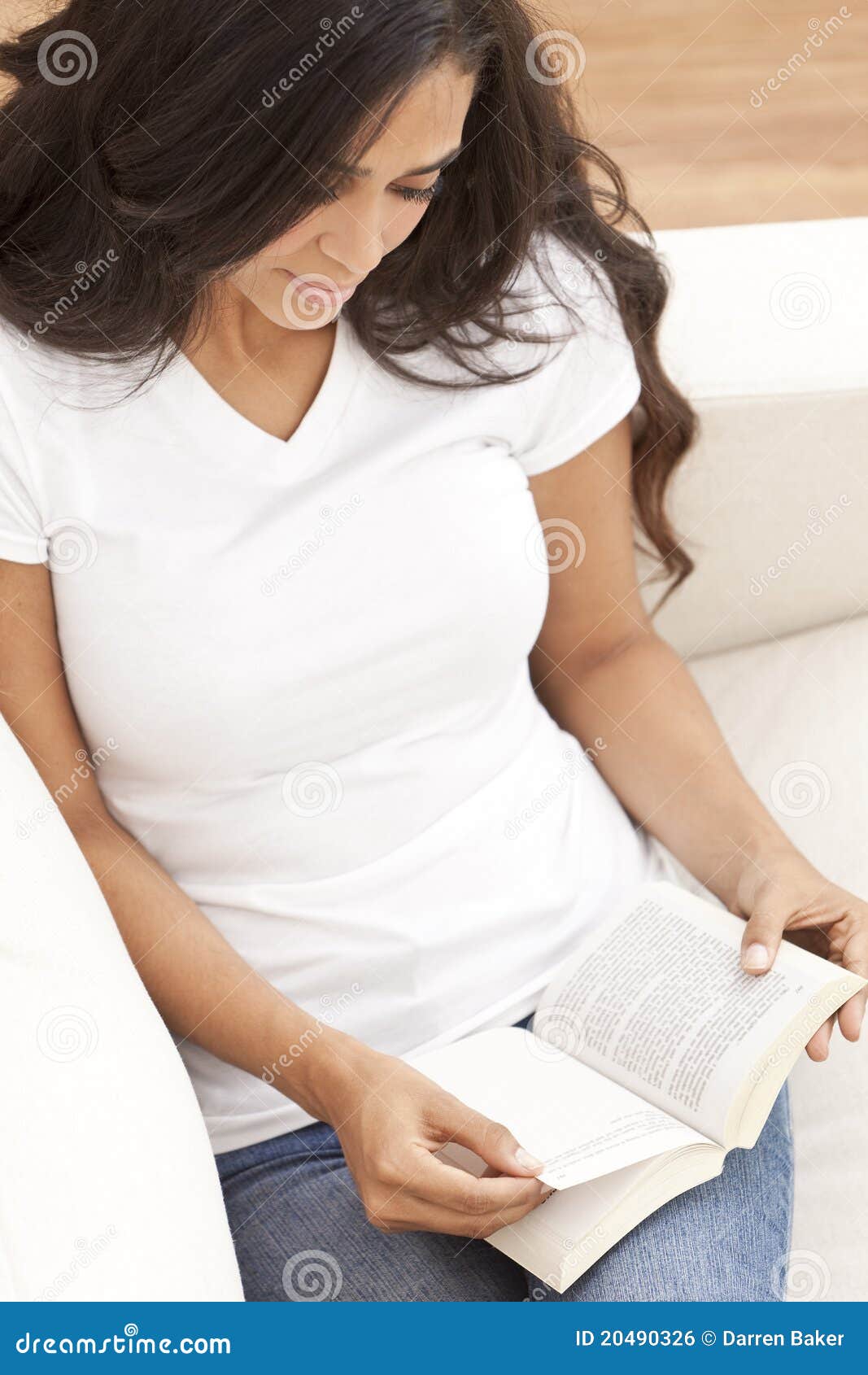 hispanic woman reading paperback book at home