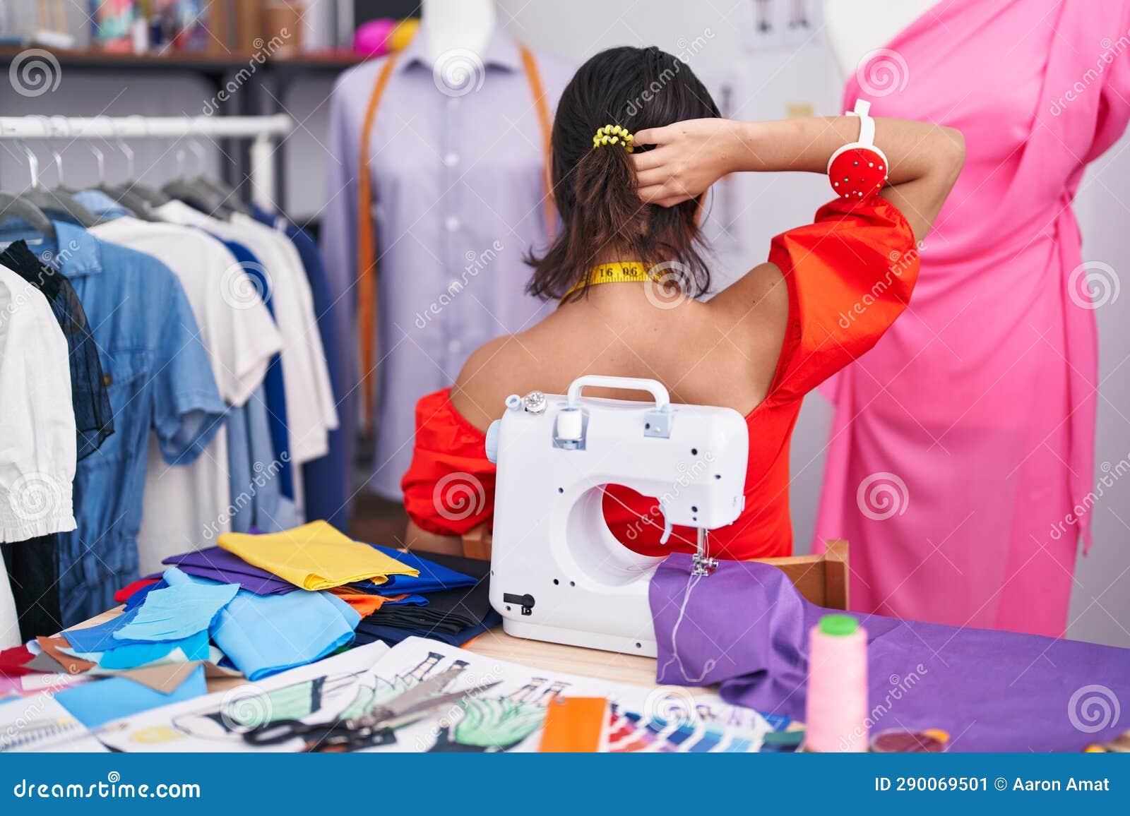 Hispanic Young Woman Dressmaker Designer Using Sewing Machine Backwards