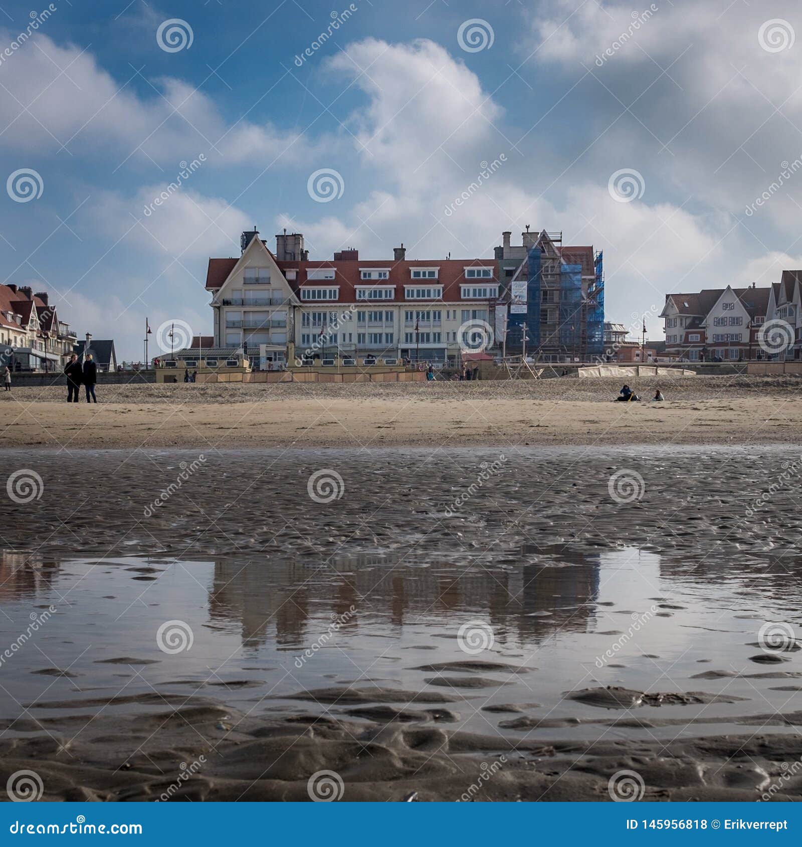 historic building in de haan, reflected in a water puddle on the beach