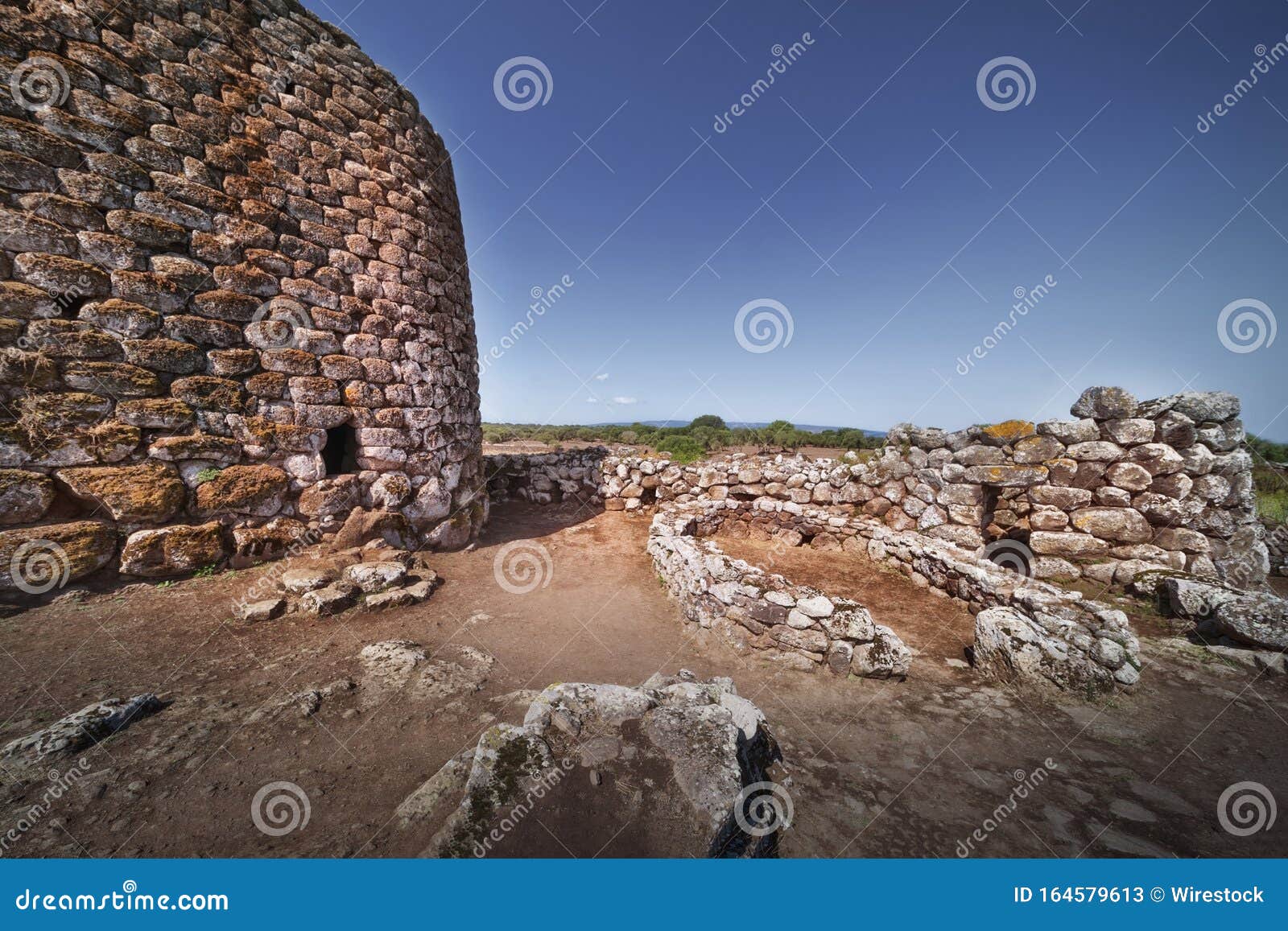 historical castle near rock formations under the clear sky in su nuraxi, sardinia, italy