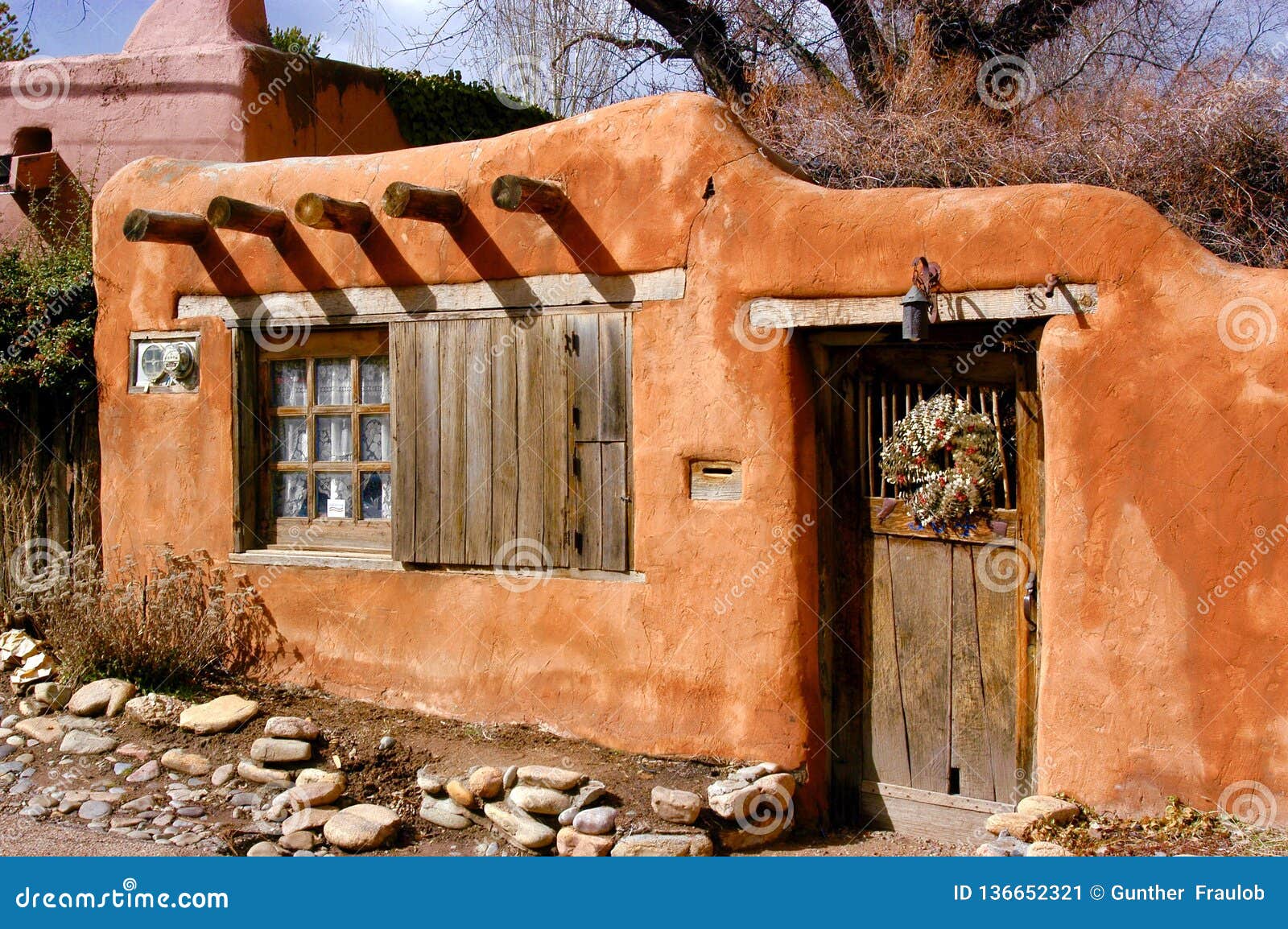historical santa fe adobe house with old styled wood beams and adobe stucco.