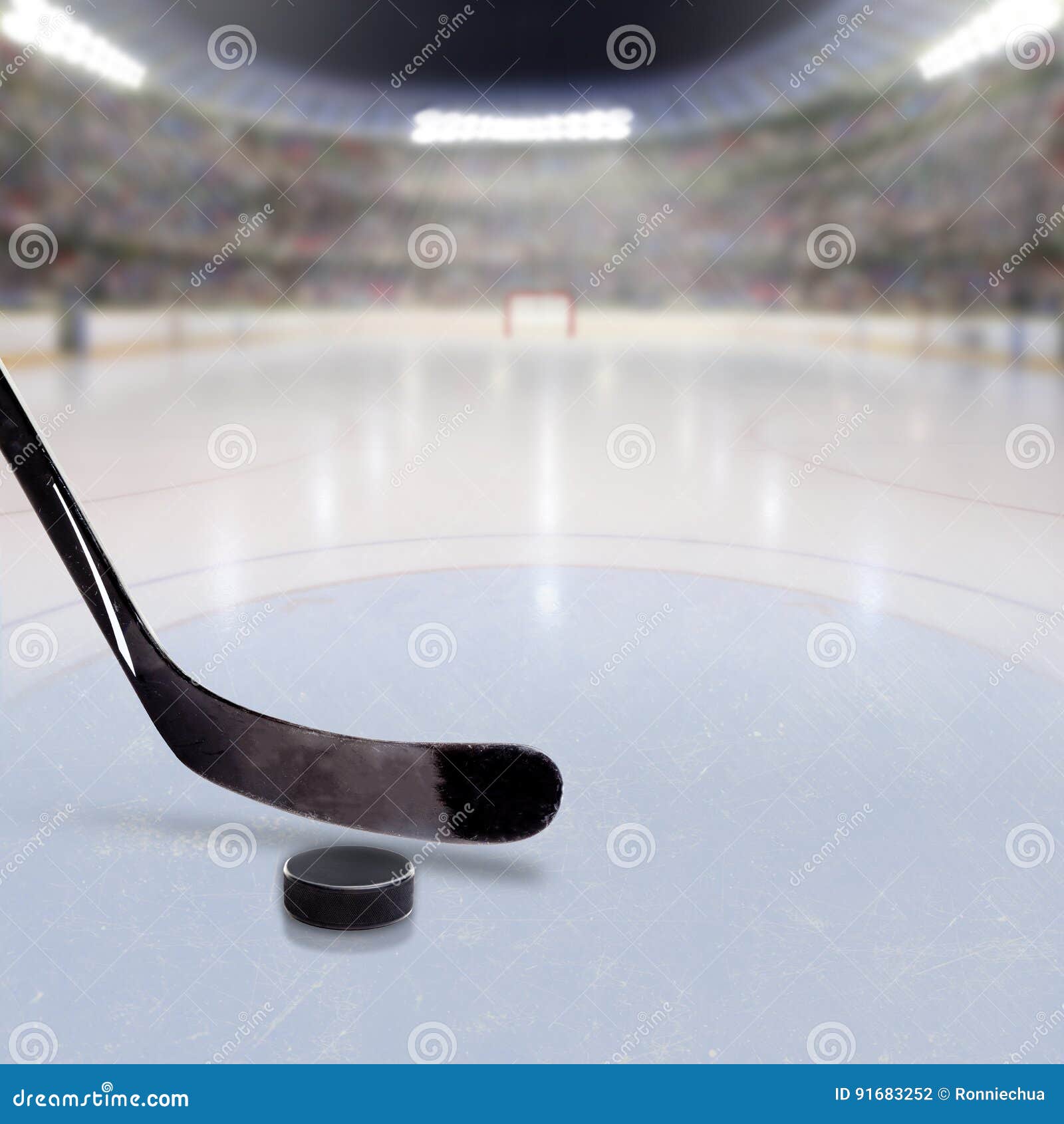 hockey stick and puck on ice of crowded arena