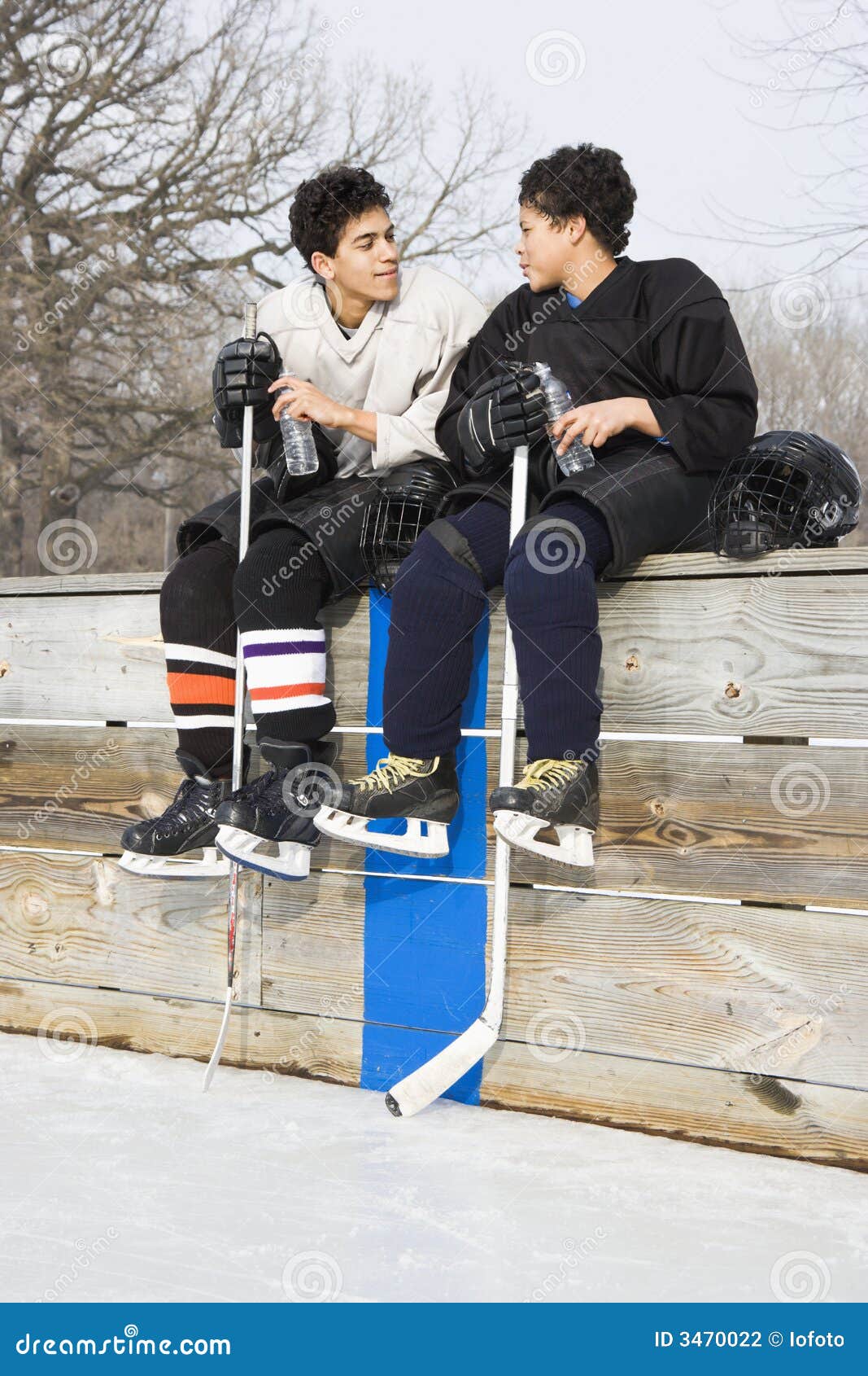 Hockeyisspelare. Isbanan för is för pojkeeachotherhockey tar ur spel sittande samtal till två likformig