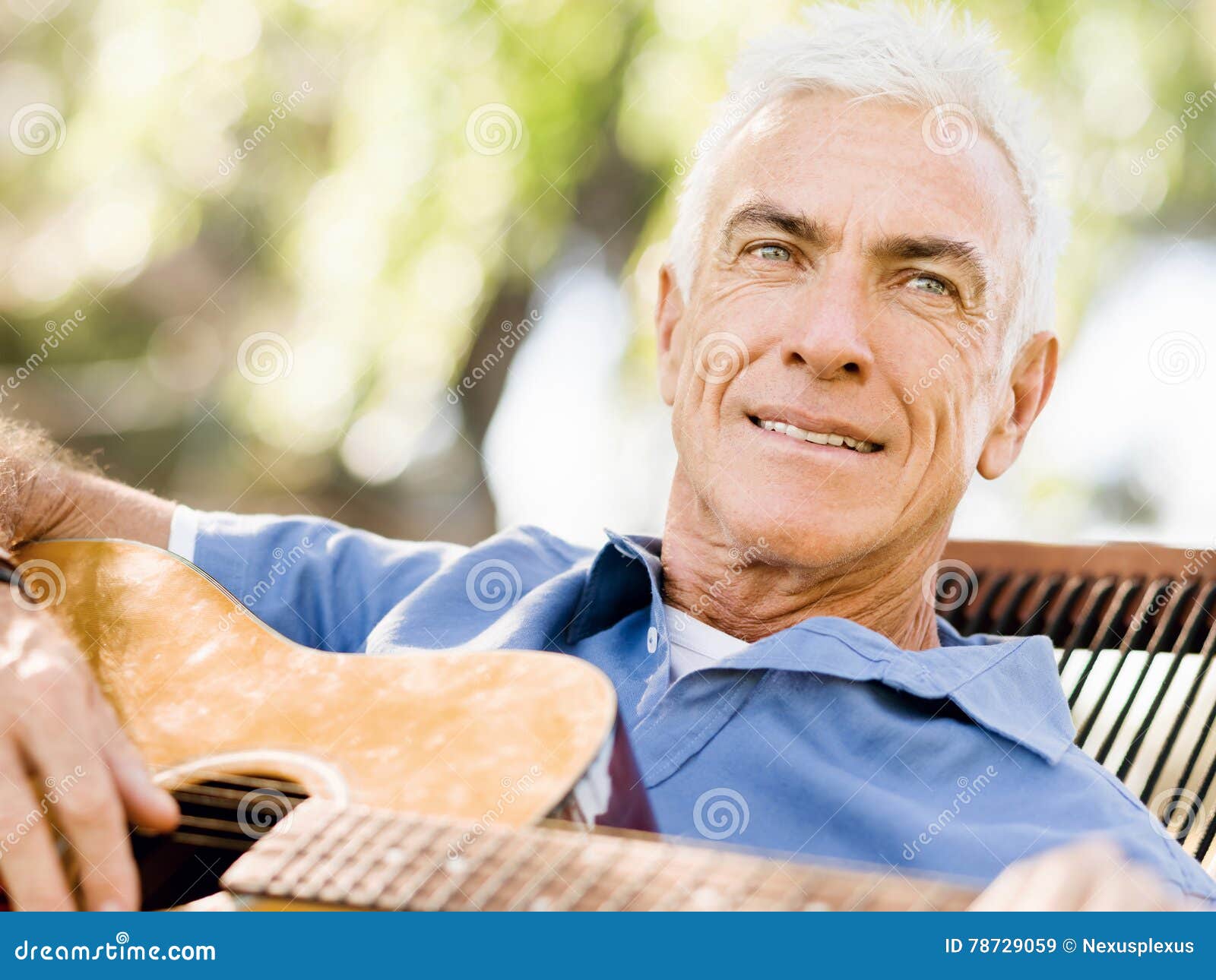 Hogere mens die gitaar in openlucht beoefenen. Knappe hogere mens het spelen gitaar in de zomerpark