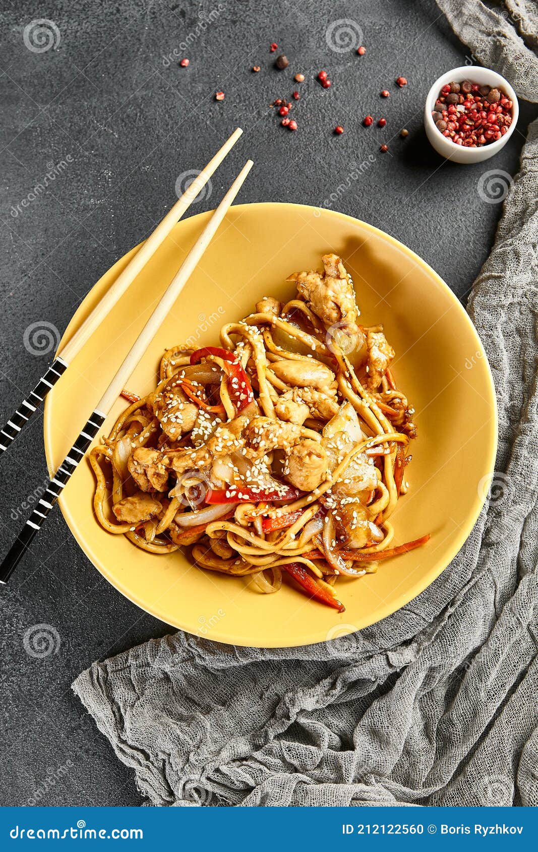 Hoisin Chicken Udon Noodles. Yellow Plate with Wooden Chopstick on Dark