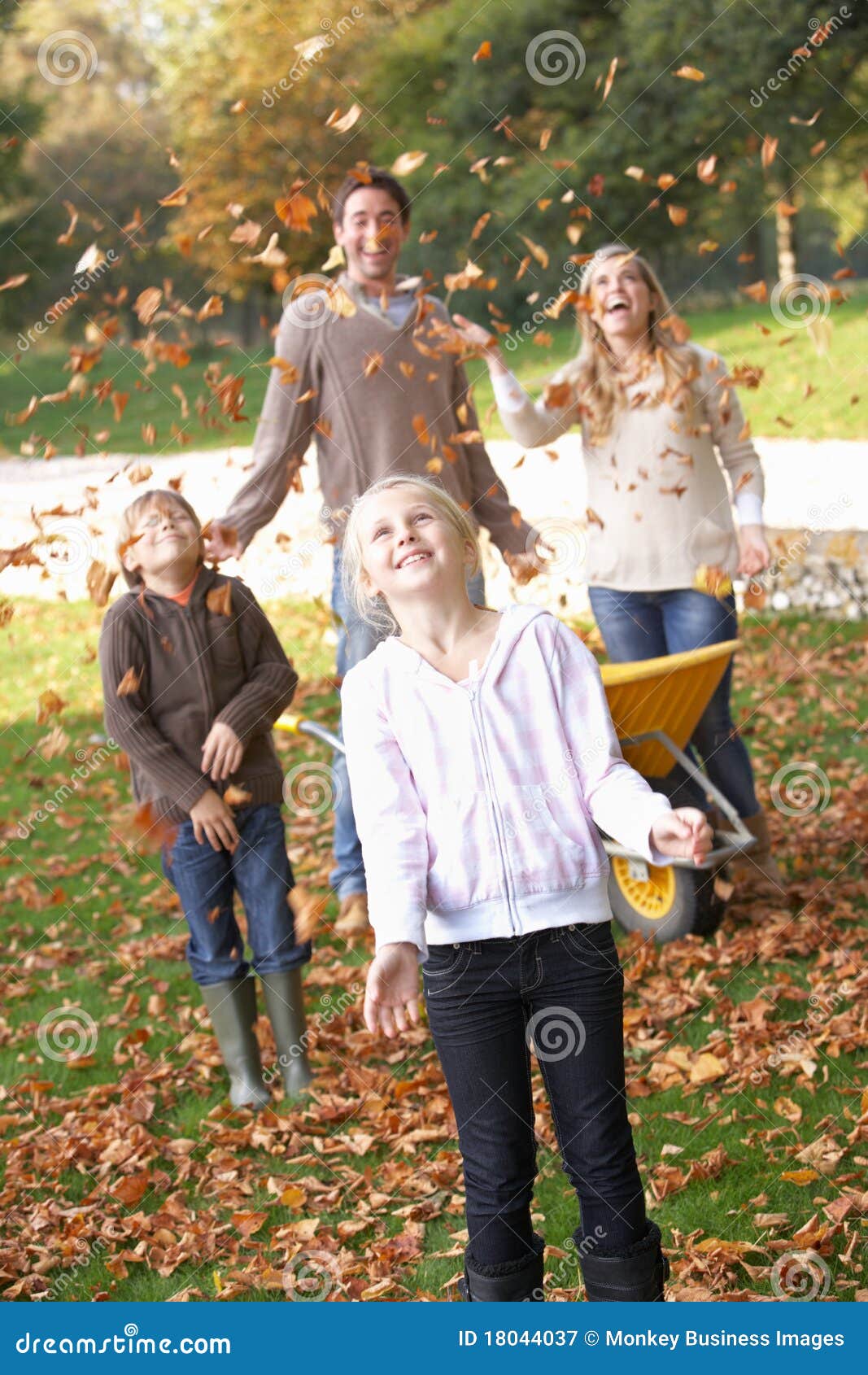 Hojas de otoño de la familia que lanzan en el aire en jardín