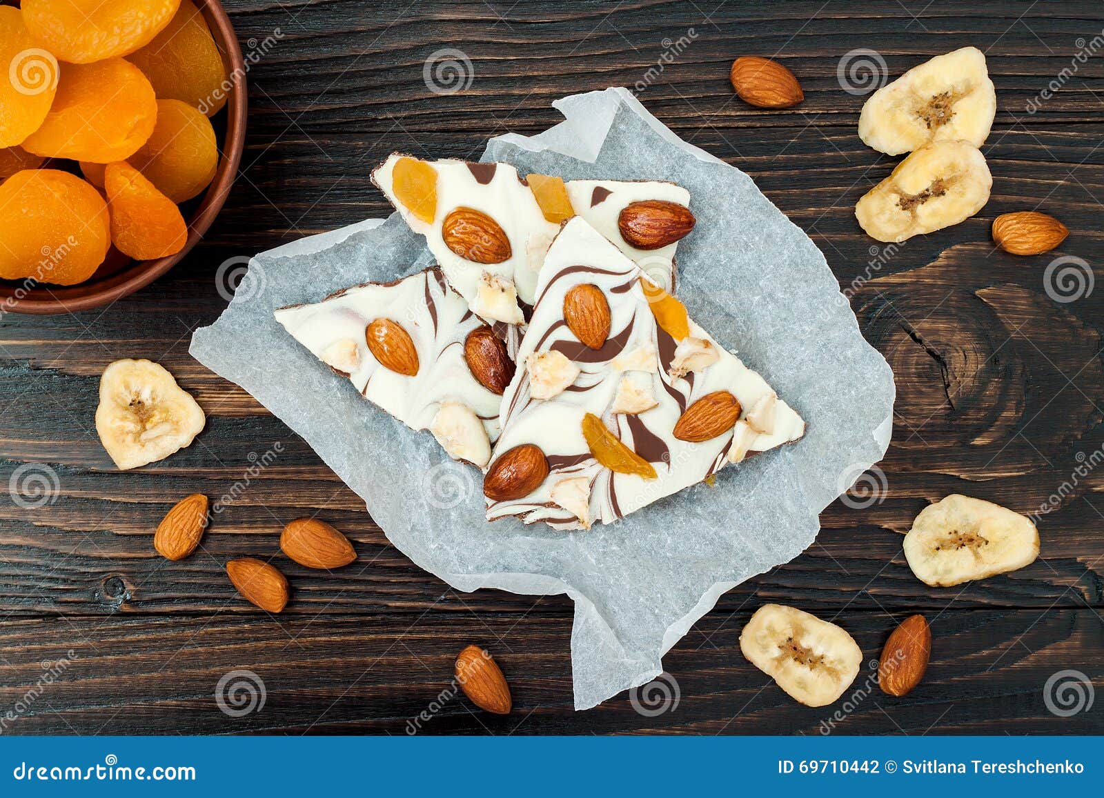 holiday chocolate bark with dried fruits and nuts on a dark wood background. top view. dessert recipe for judaic holiday tu bishva