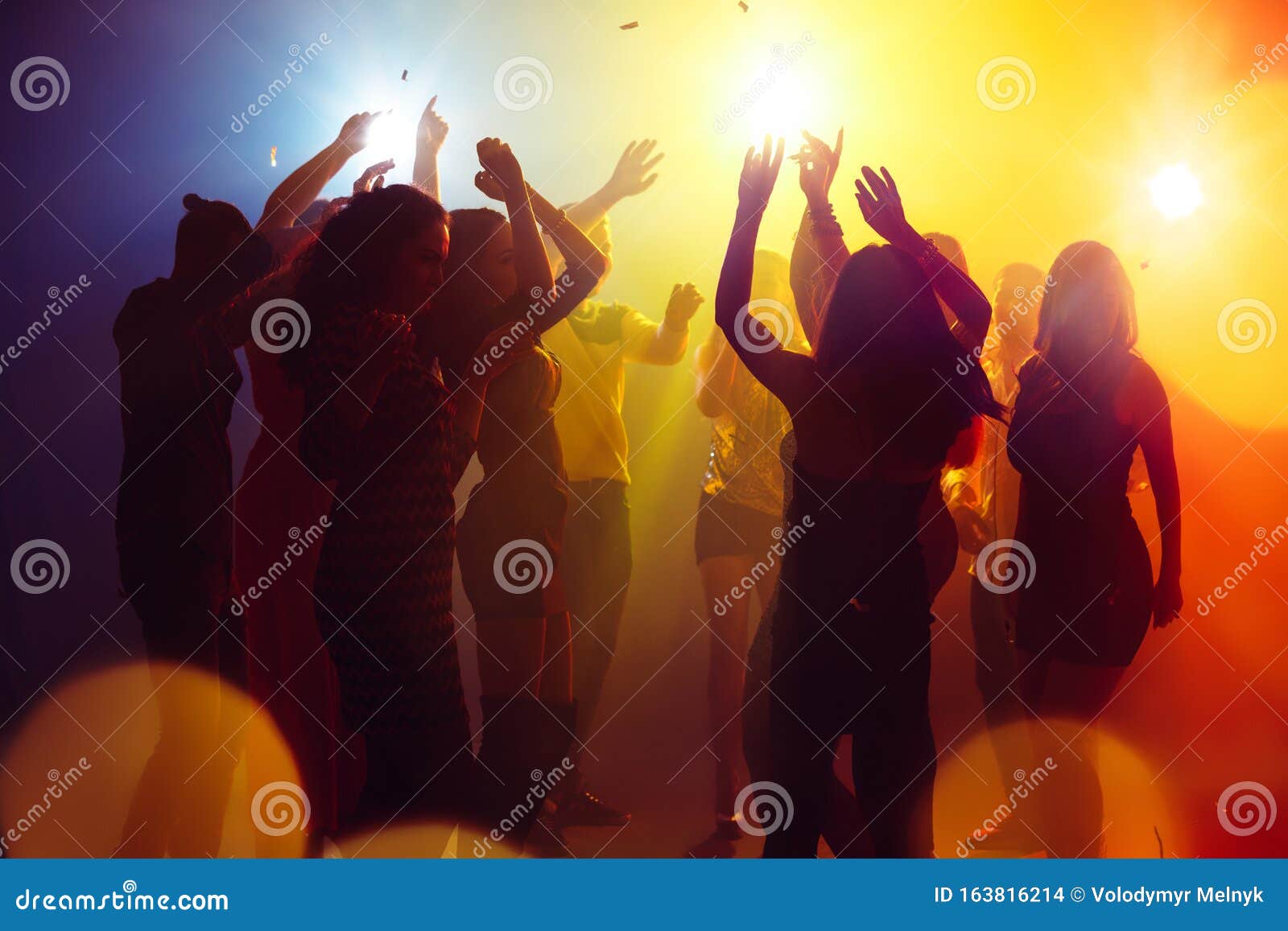 A Crowd of People in Silhouette Raises Their Hands Against Colorful ...