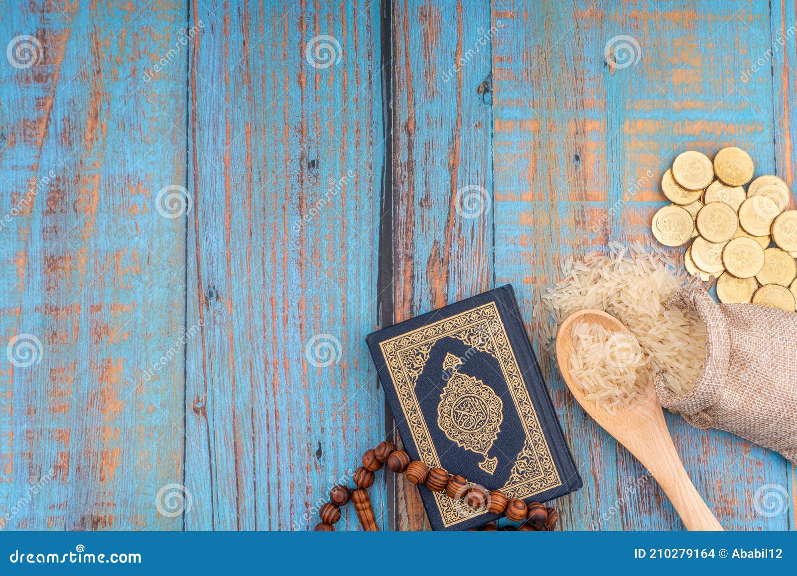 holy quran with arabic calligraphies translation meaning of al-quran, coins, rosary and rice. zakat concept.
