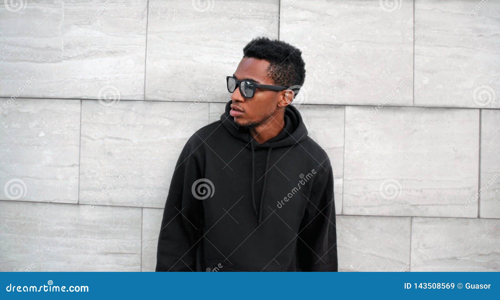 Hombre Africano Del Retrato En La Sudadera Con Capucha Negra, Gafas De Sol  Que Miran Lejos En La Calle De La Ciudad Sobre La Pare Imagen de archivo -  Imagen de moderno