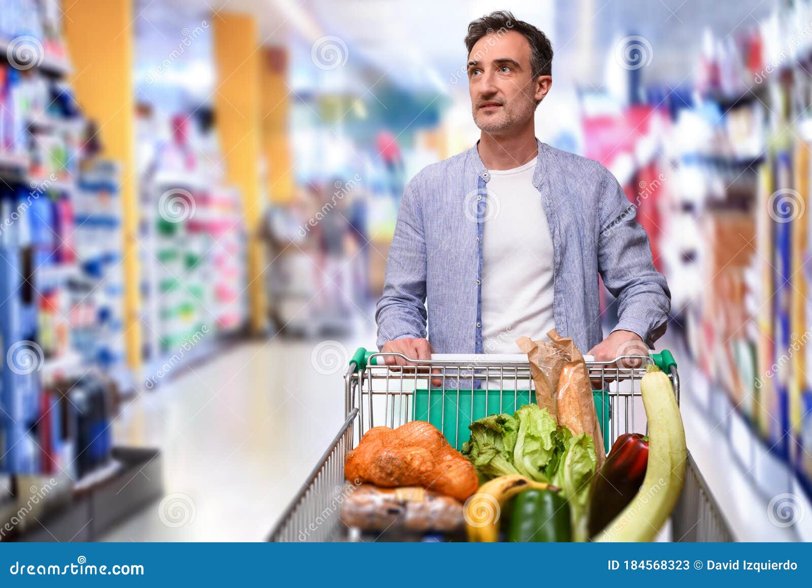 Hombre Comprando Y Empujando Un Carro De La Compra En Un Supermercado  Imagen de archivo - Imagen de consumerismo, compra: 184568323