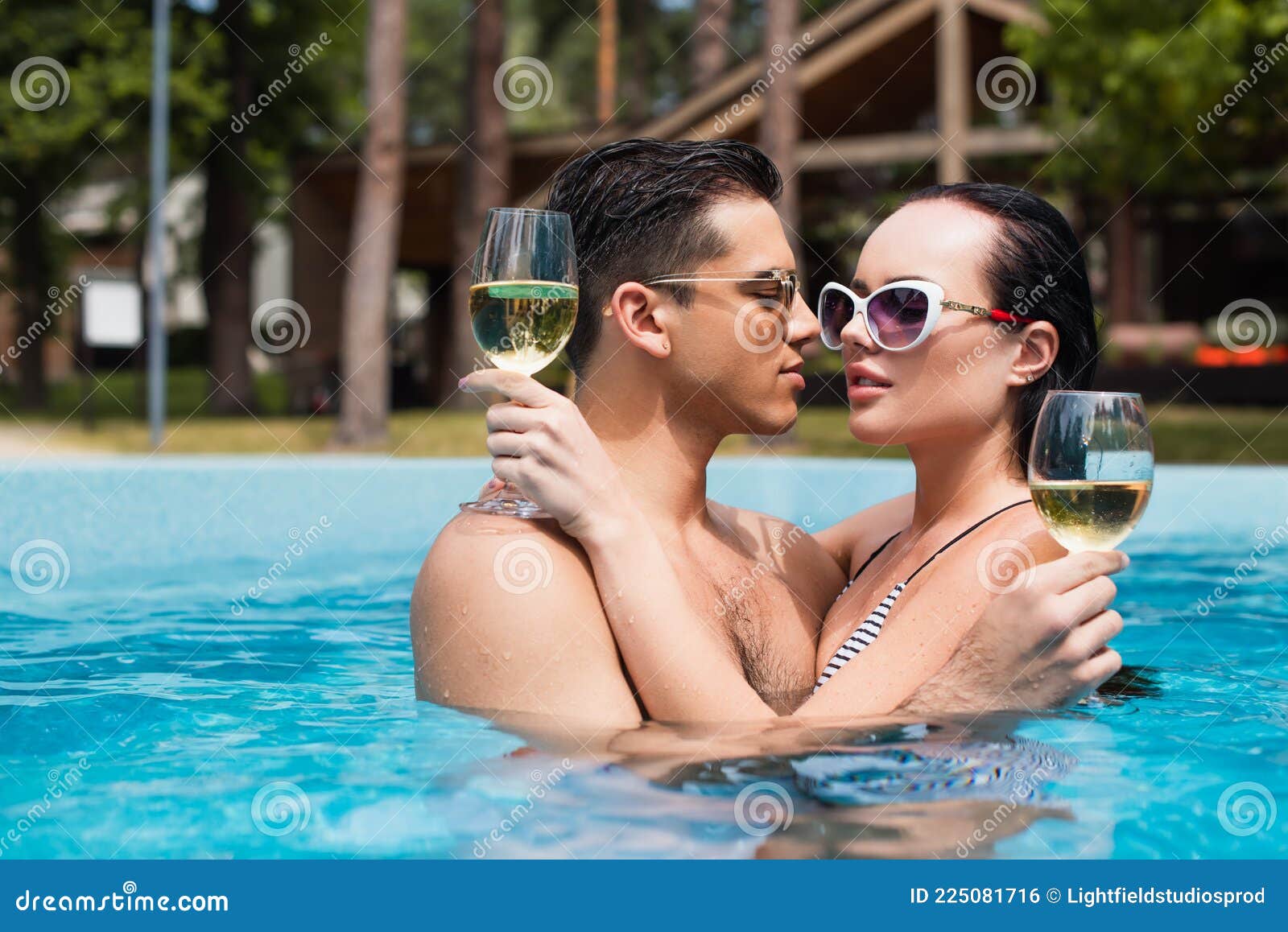 Hombre con gafas de sol sonriendo en la piscina Stock Photo