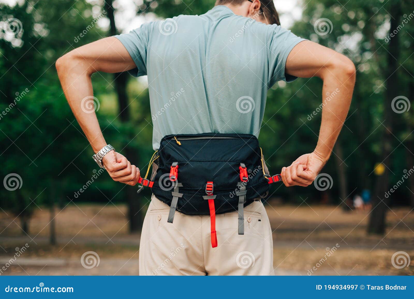 Hombre Con Ropa Informal Se Pone En Pie En El Bosque Durante El Día Y Se  Aferra a Una Bolsa De Cintura. Turista Con Una Bolsa De C Imagen de archivo  