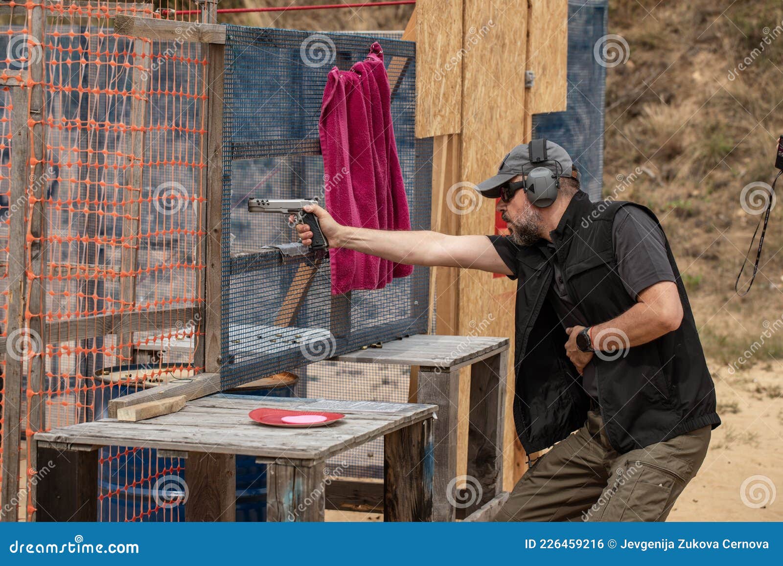 Hombre con ropa táctica disparando desde una pistola, volviendo a cargar la  pistola y apuntando al objetivo en la zona de tiro de puerta abierta  Fotografía de stock - Alamy