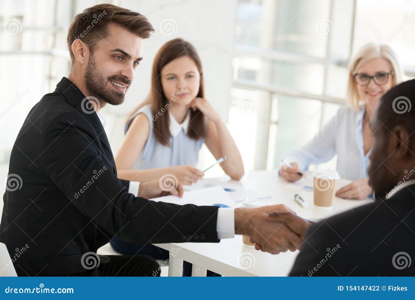 Hombre de negocios confiado que sacude al colega de la mano en la reunión de compañía. El hombre de negocios confiado que sacude al colega afroamericano de la mano en la reunión de compañía en la sala de reunión, empleado que saluda, presentando o consiguiendo al socio comercial conocido en oficina, felicita, se cierra para arriba