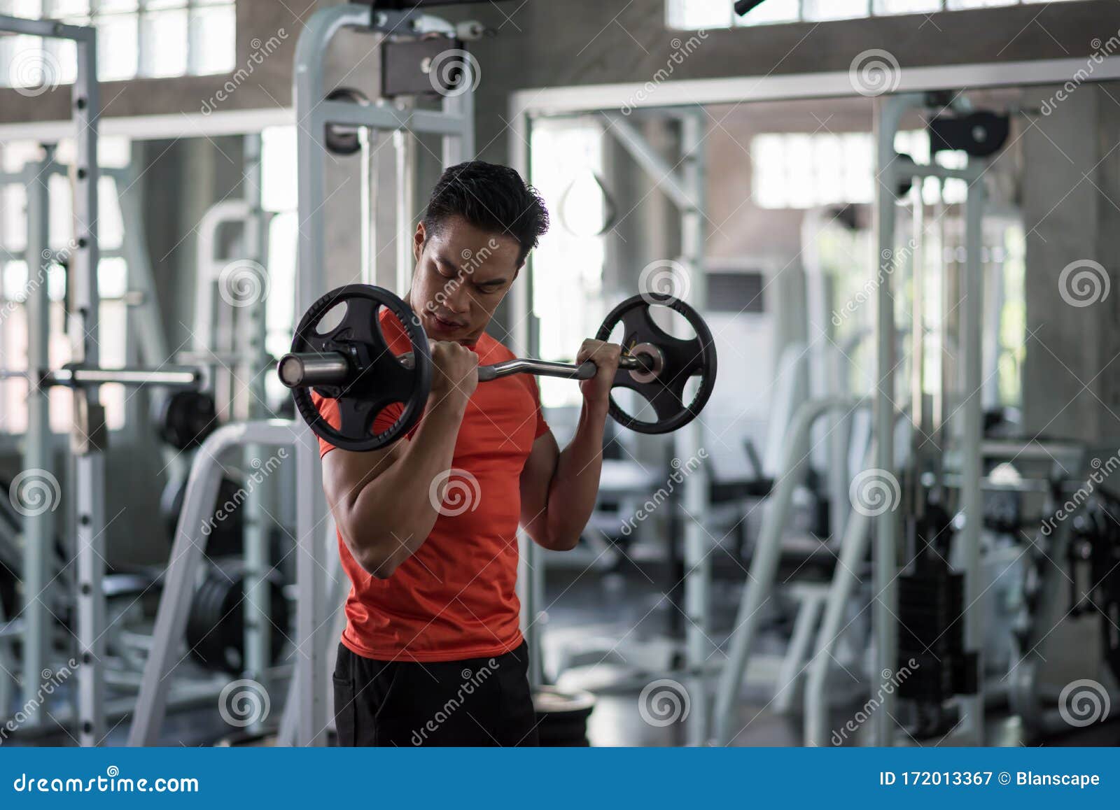 Hombre musculoso trabajando con placa de barra para hacer ejercicio en el  gimnasio.