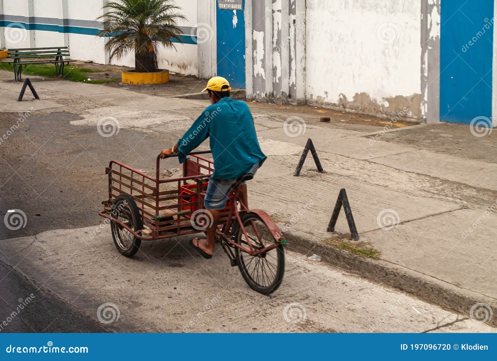 hombre-en-el-triciclo-de-entrega-manta-ecuador-diciembre-vestido-con-una-gorra-azul-y-amarilla-un-rojo-la-calle-paredes-197096720.jpg