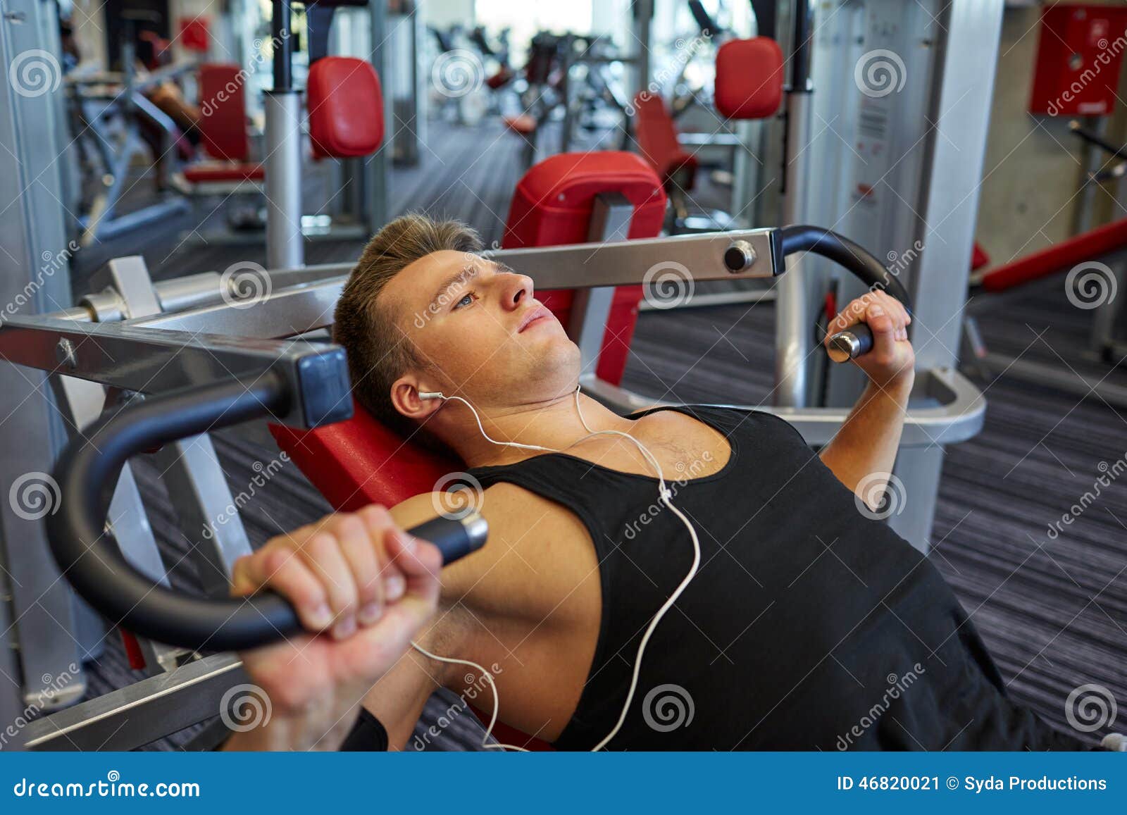 Hombre Joven Con Los Auriculares Que Ejercita En La Máquina Del Gimnasio  Imagen de archivo - Imagen de gente, deportista: 46820021